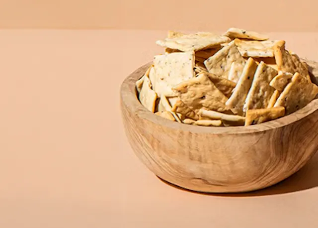 eine Holzschüssel mit Crackern auf einem Tisch .