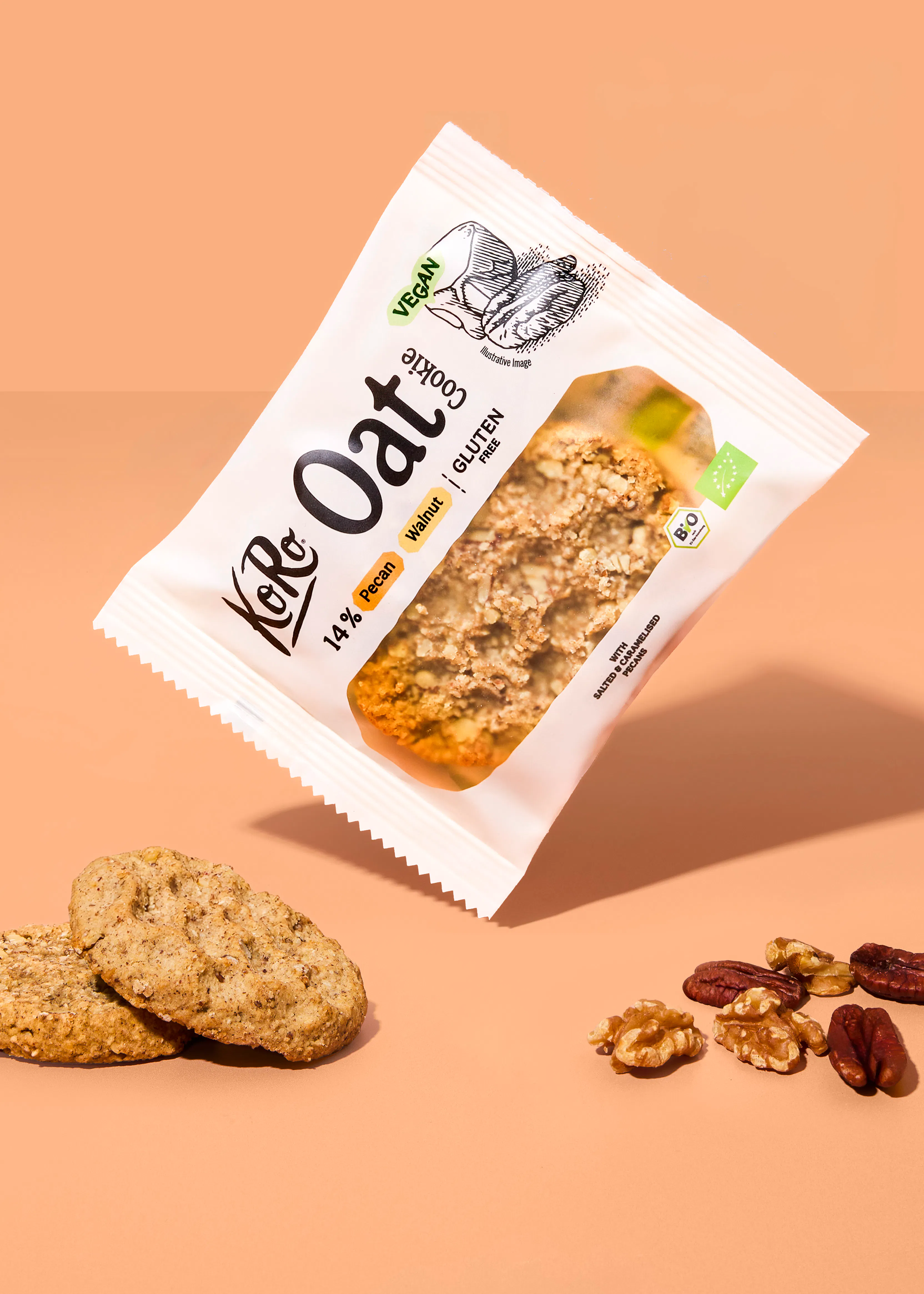 eine packung koro oat cookie mit pekannüssen und walnüssen schwebt über zwei ausgepackten keksen und einigen nusskernen auf einem beigen hintergrund.