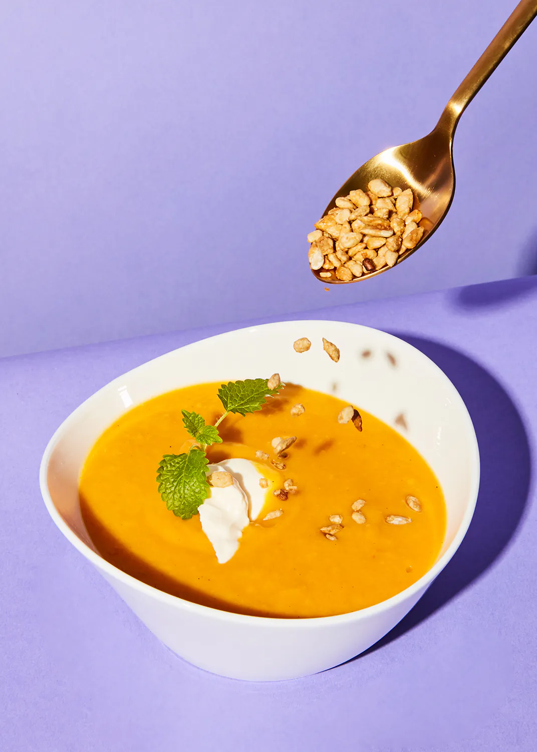 un bol de soupe avec des graines de citrouille et de la crème fouettée