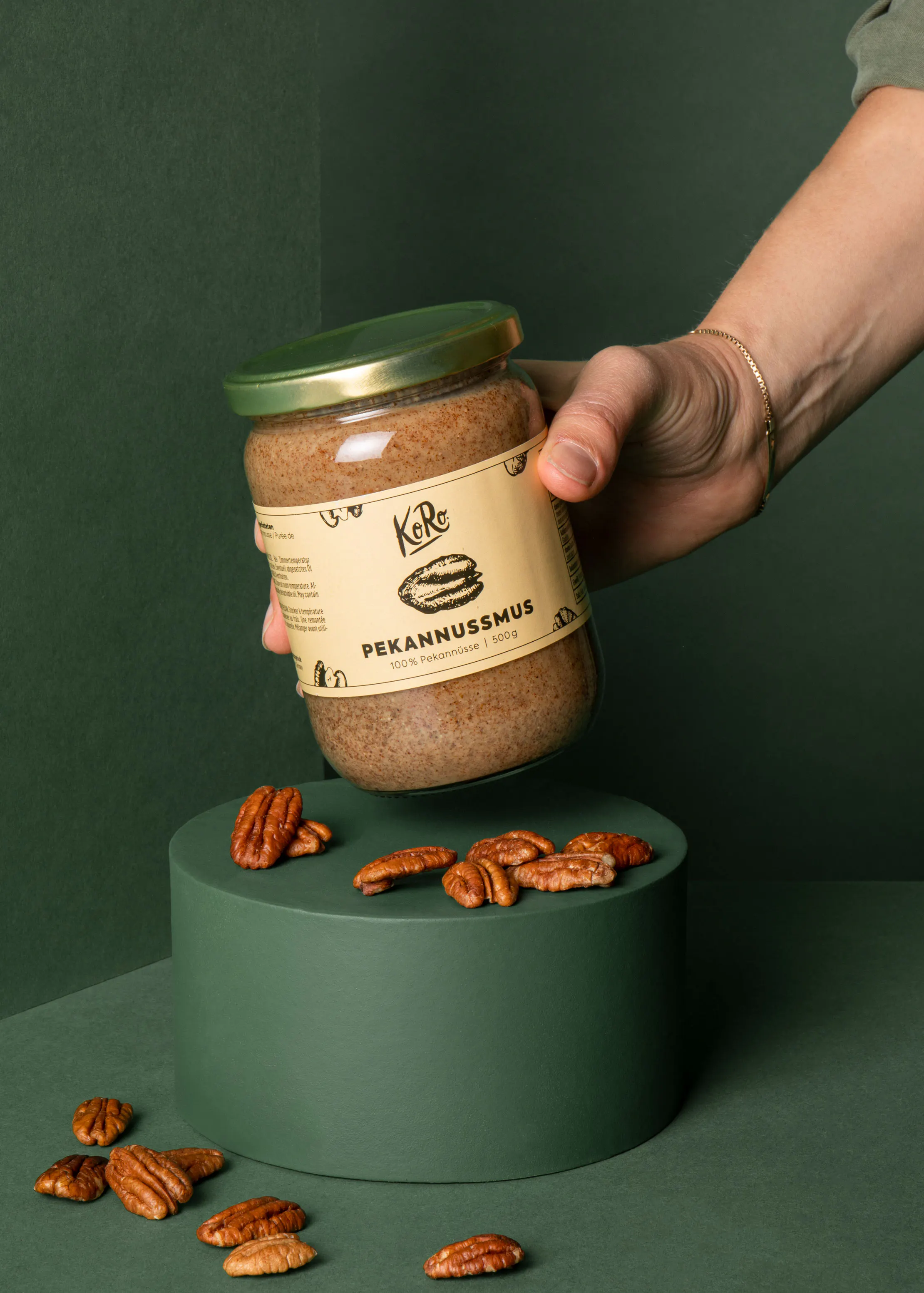 une personne tient un bocal de pekannusmus sur une table verte