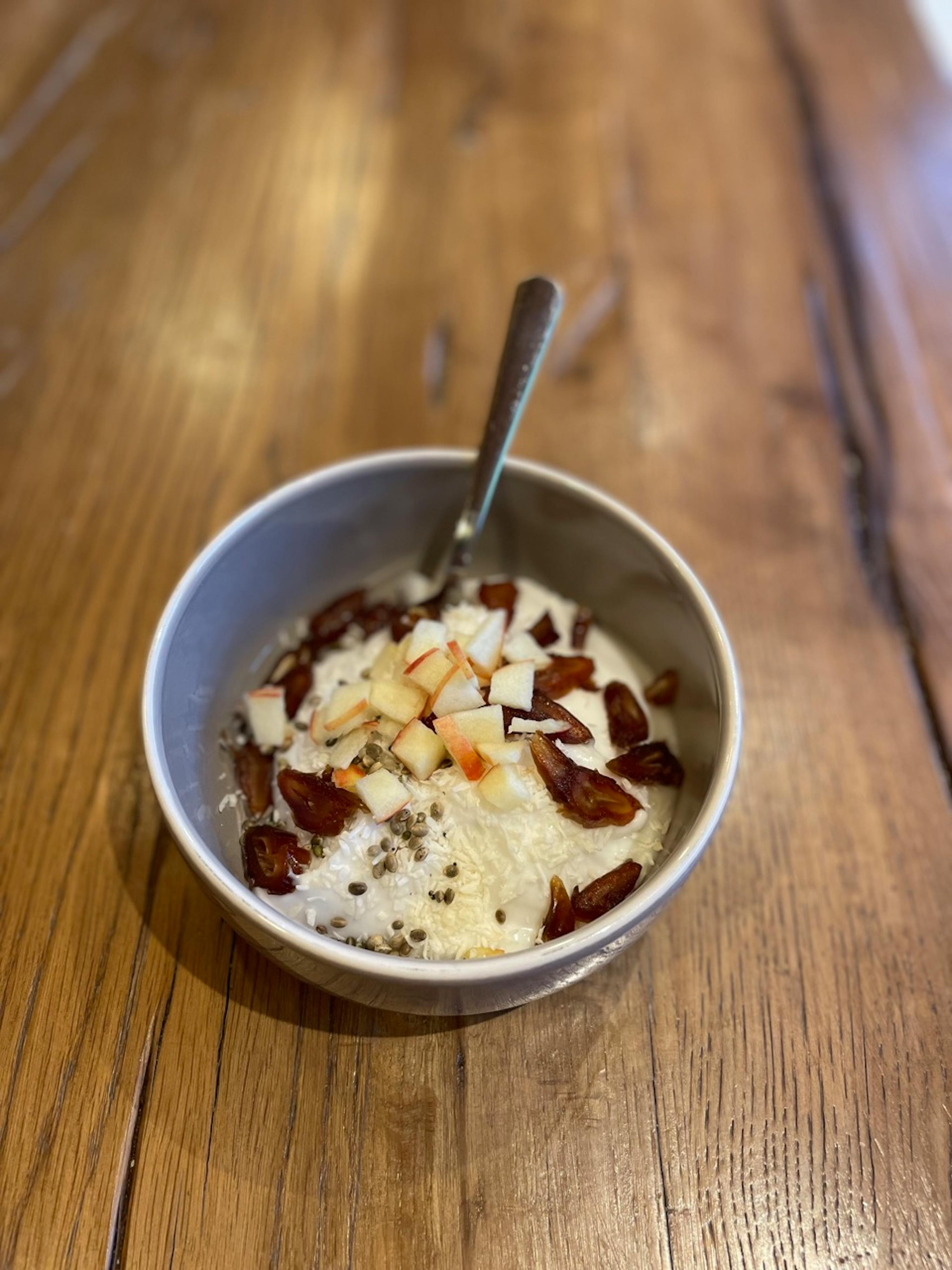 a bowl of food on a wooden table with a spoon in it