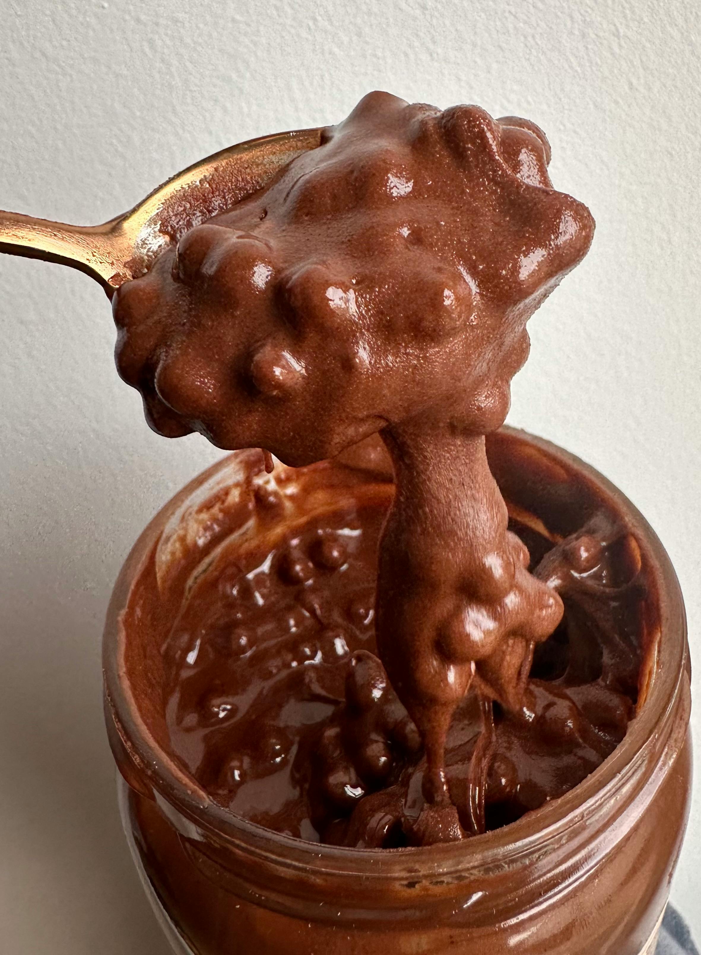 une cuillère remplie de pâte au chocolat sort d' un bocal