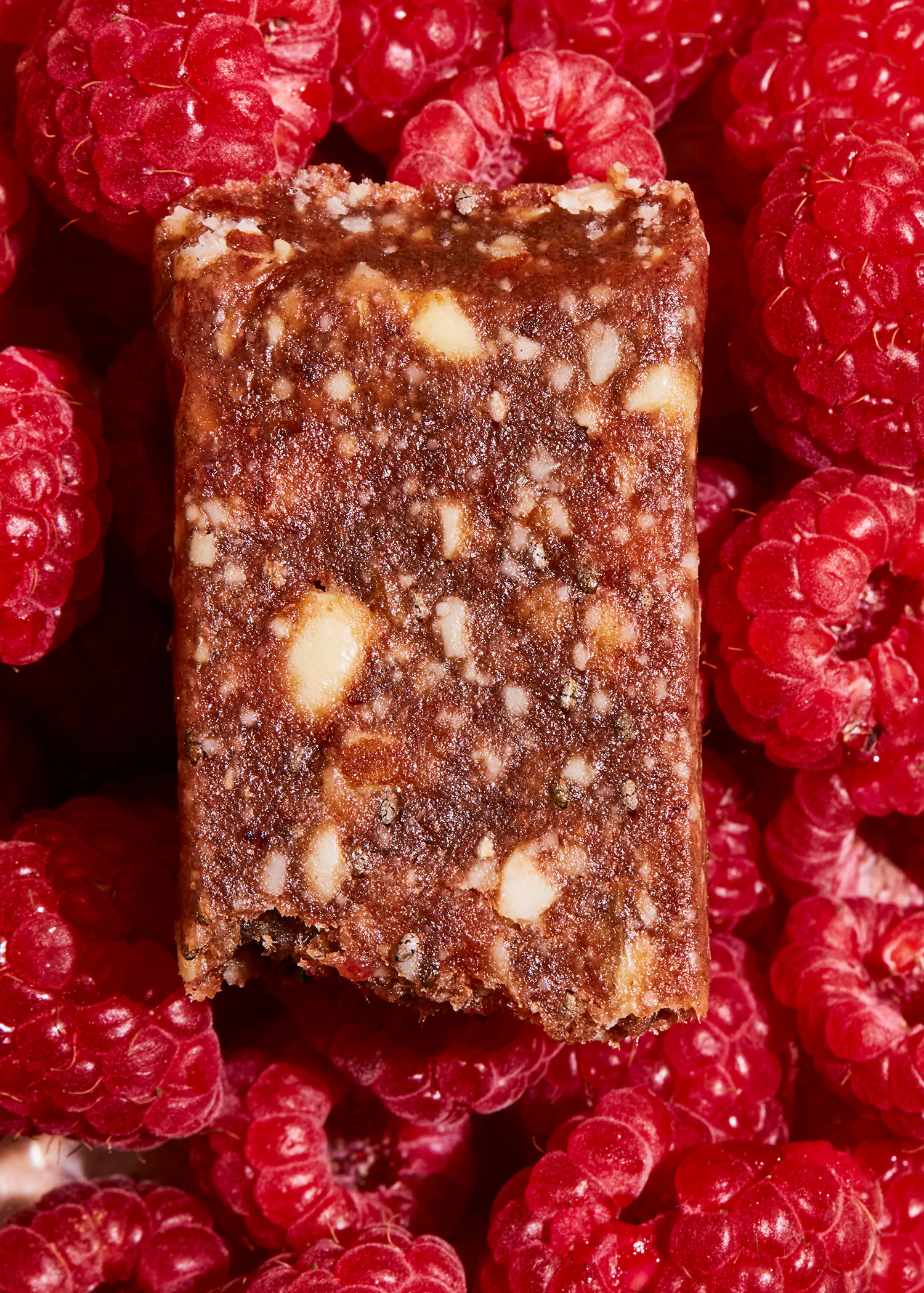a close up of a piece of food surrounded by raspberries