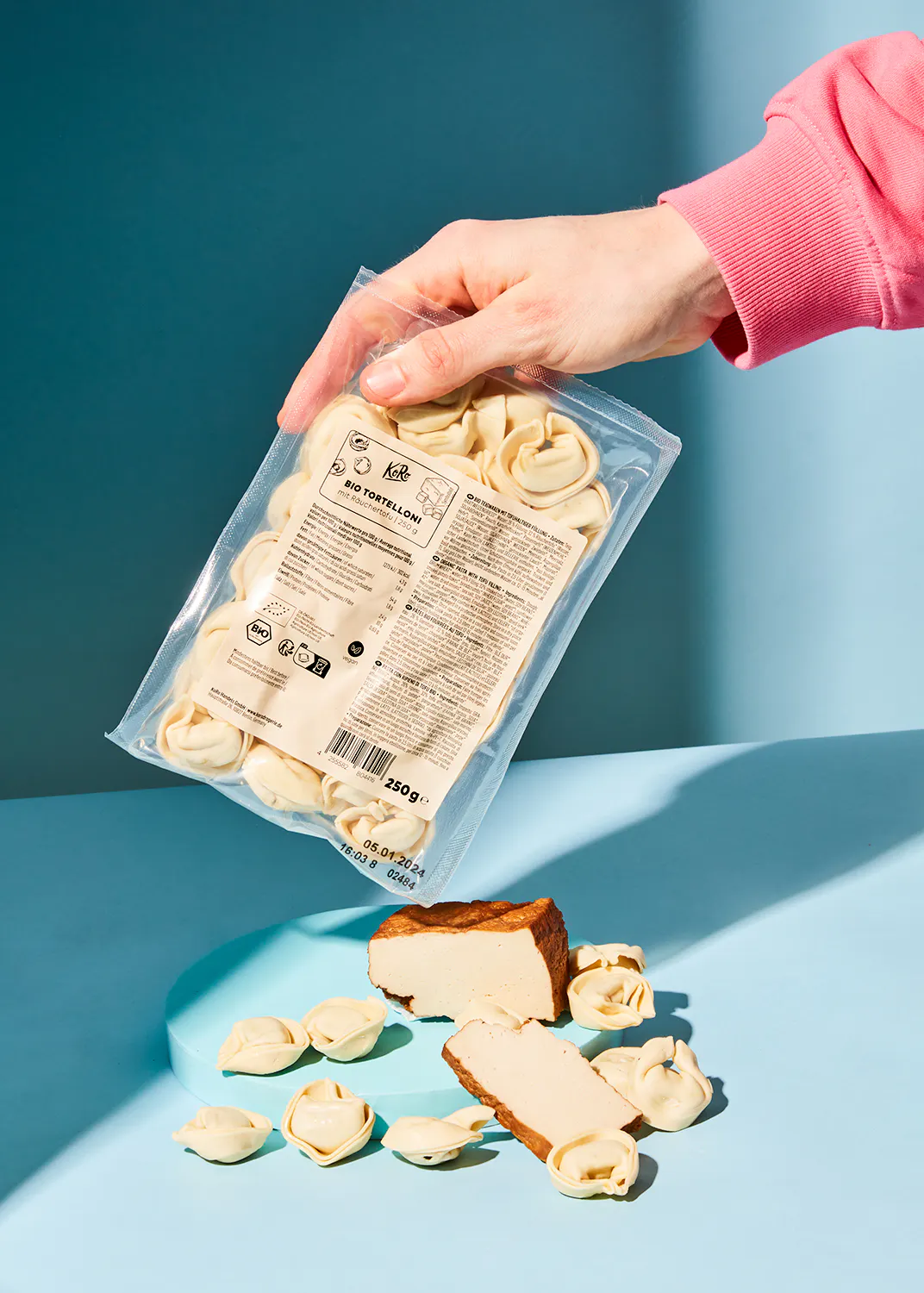 une personne tient un sac de raviolis à côté d' un morceau de fromage