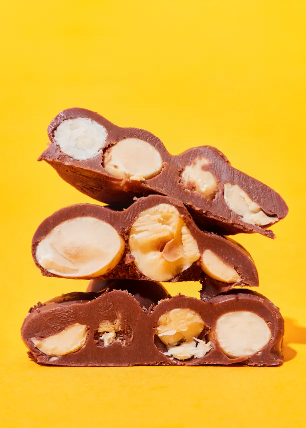 a stack of chocolates with nuts in them on a yellow background