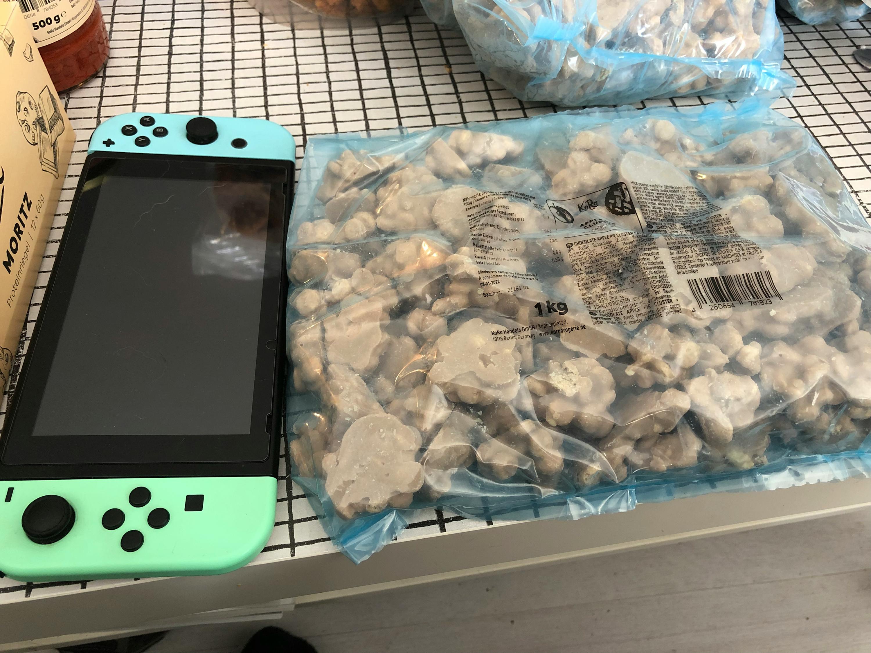 une nintendo switch verte est assise à côté d' un sac de pop-corn