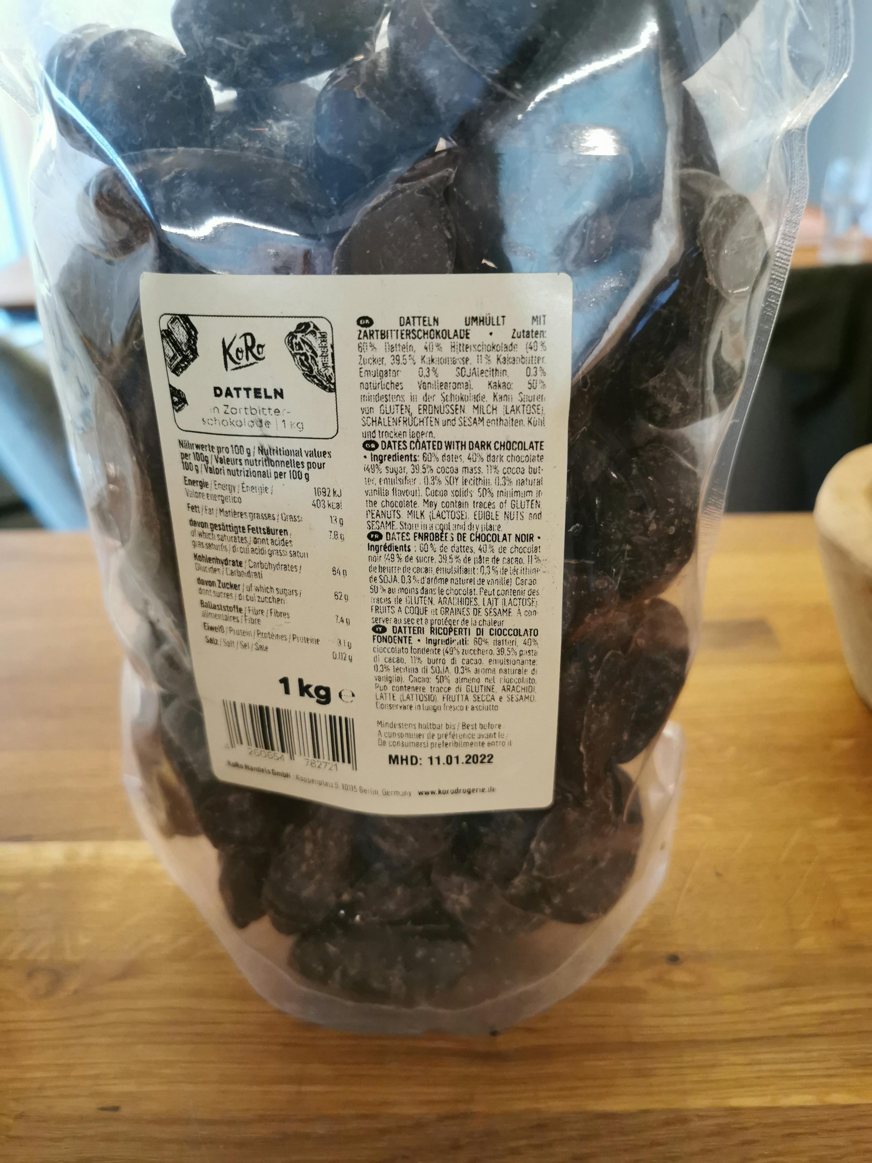 un sacchetto di datteri ricoperti di cioccolato al latte è su un tavolo di legno