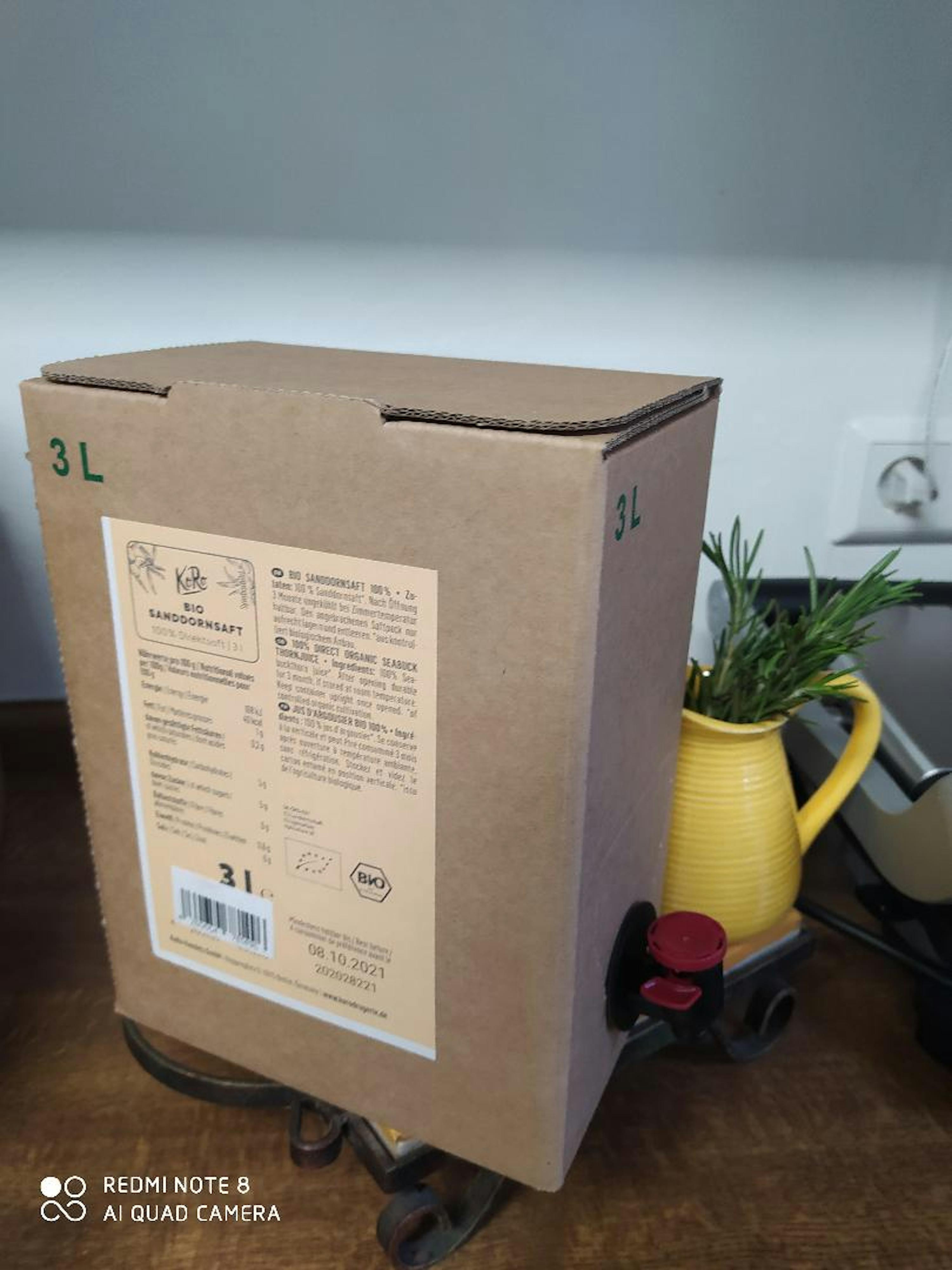 una scatola di cartone con l' etichetta 3l è seduta su un tavolo accanto a una brocca gialla