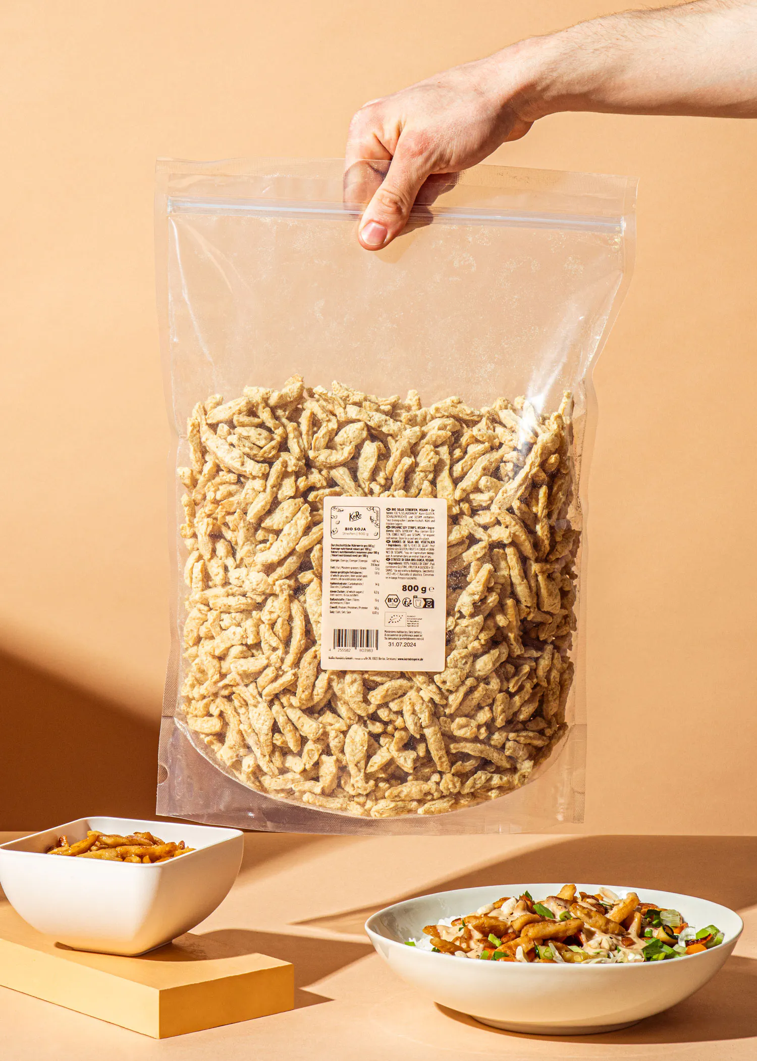 una persona sostiene una bolsa de fideos de soja junto a un plato de comida