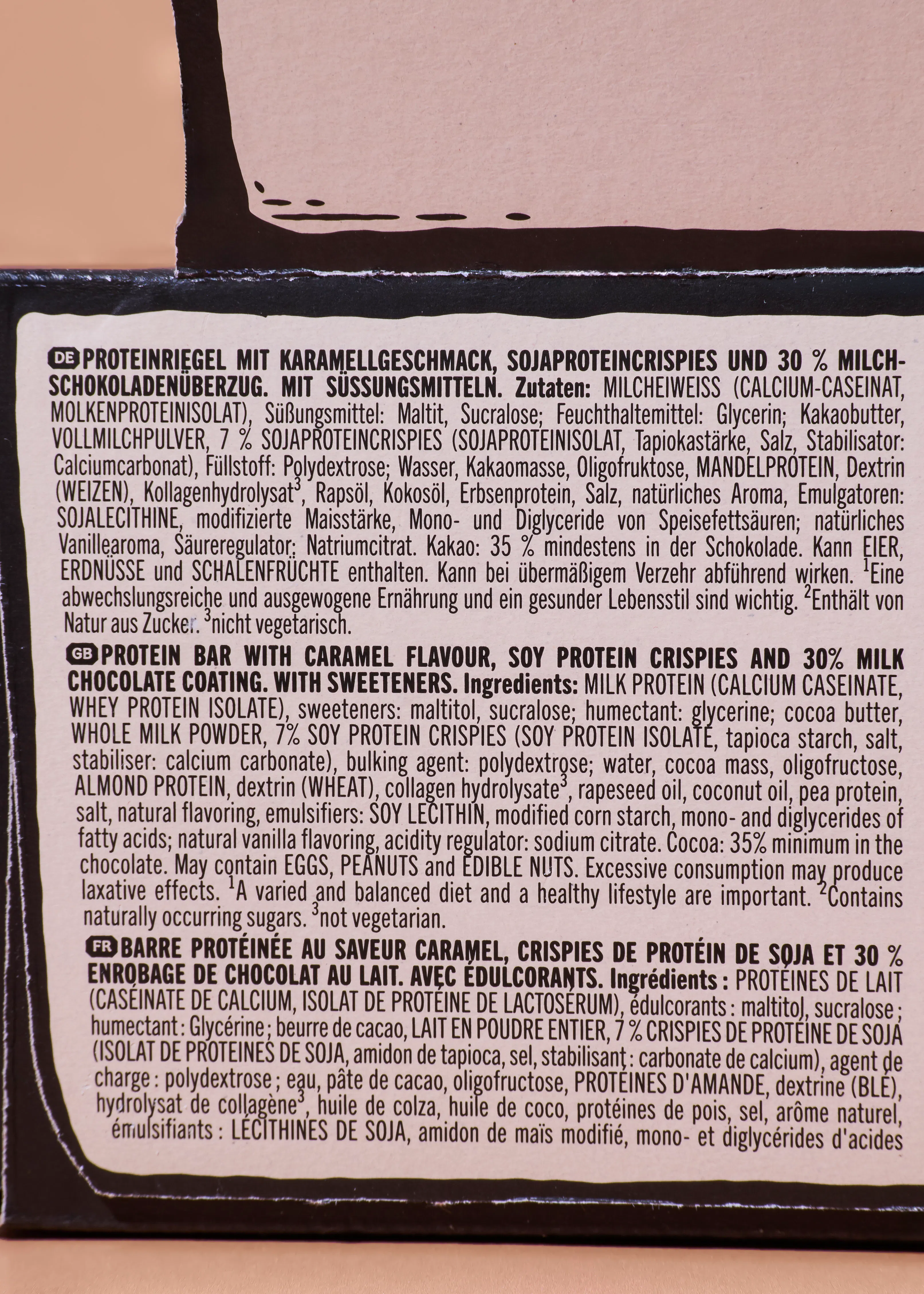 liste des ingrédients et informations nutritionnelles pour une barre protéinée au caramel, crispies de protéines de soja et enrobage de chocolat au lait, avec édulcorants, présentée en allemand, anglais et français.