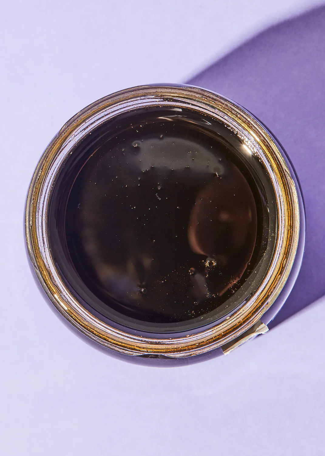 a close up of a jar of liquid with a gold rim