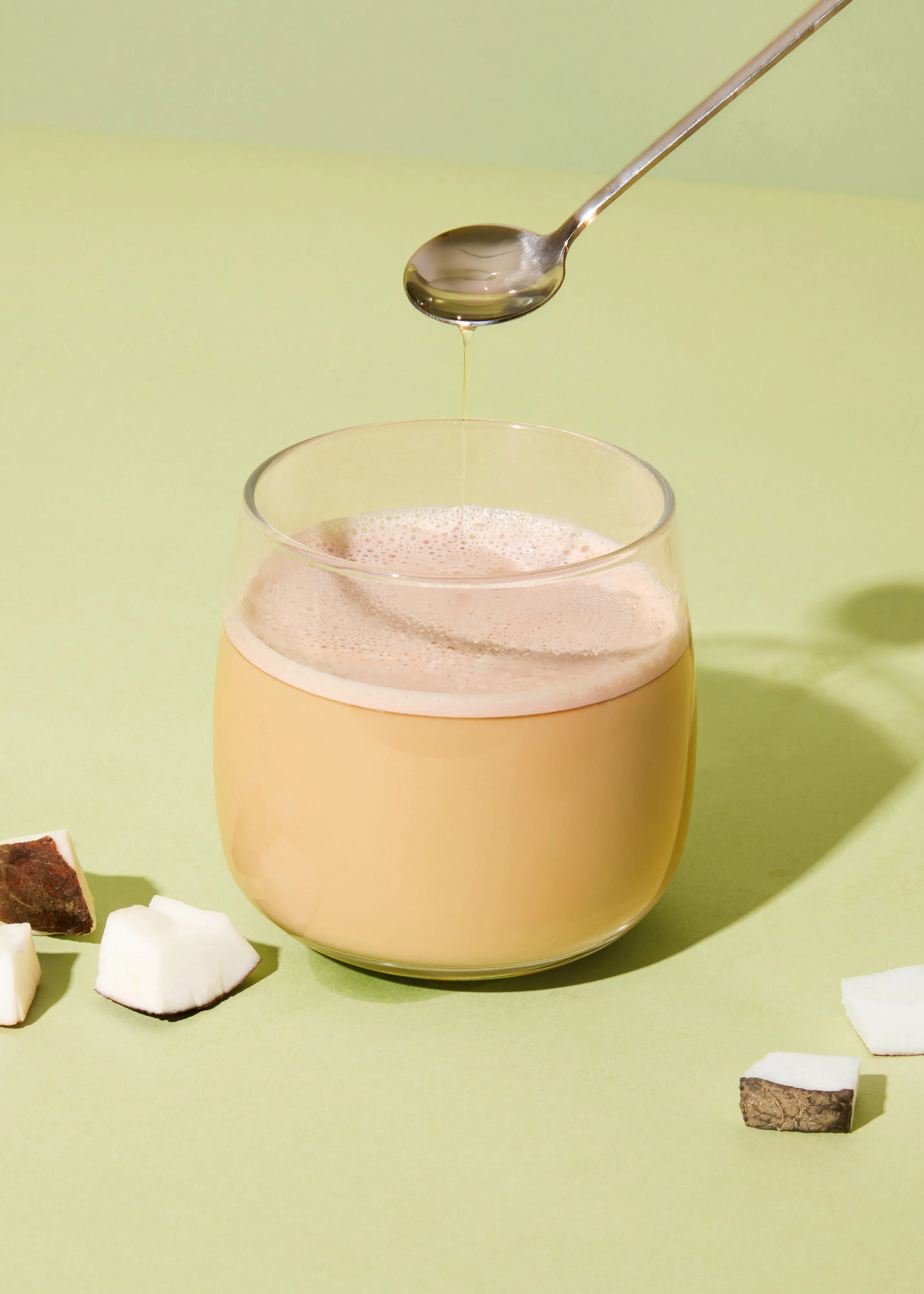 un bicchiere di latte con un cucchiaio che versa lo sciroppo