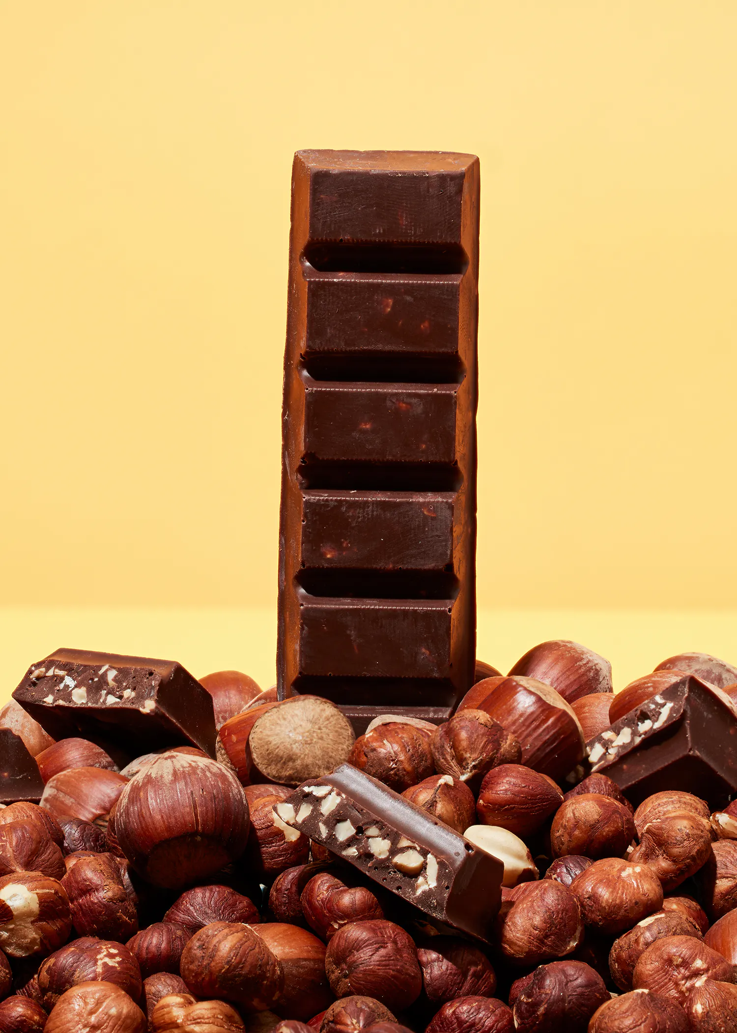 une barre de chocolat est assise sur une pile de noisettes