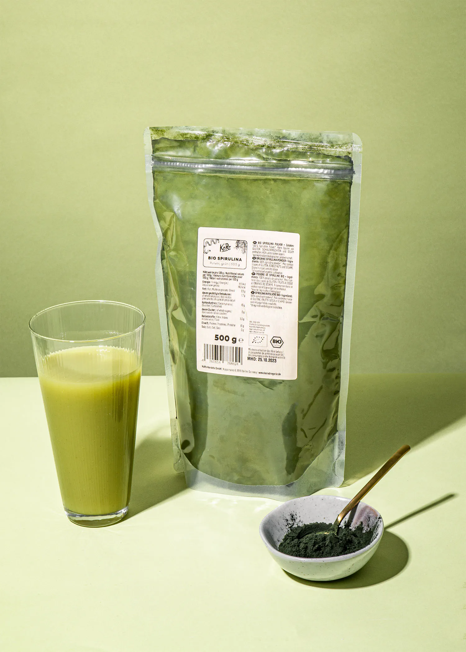 un sac de spirulina est assis à côté d' un verre de boisson
