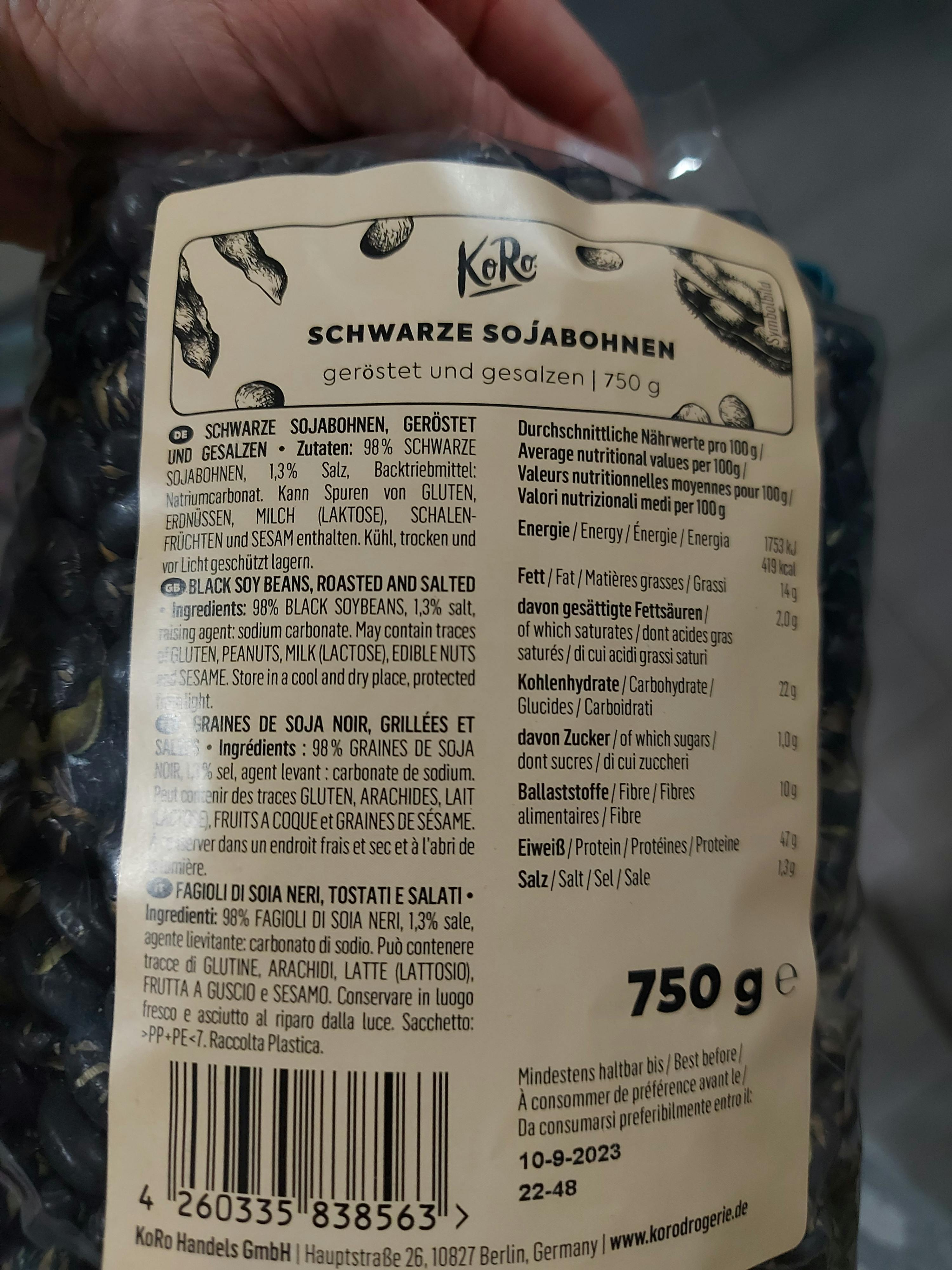 eine Person hält eine Tüte schwarze sojabohnen in der Hand