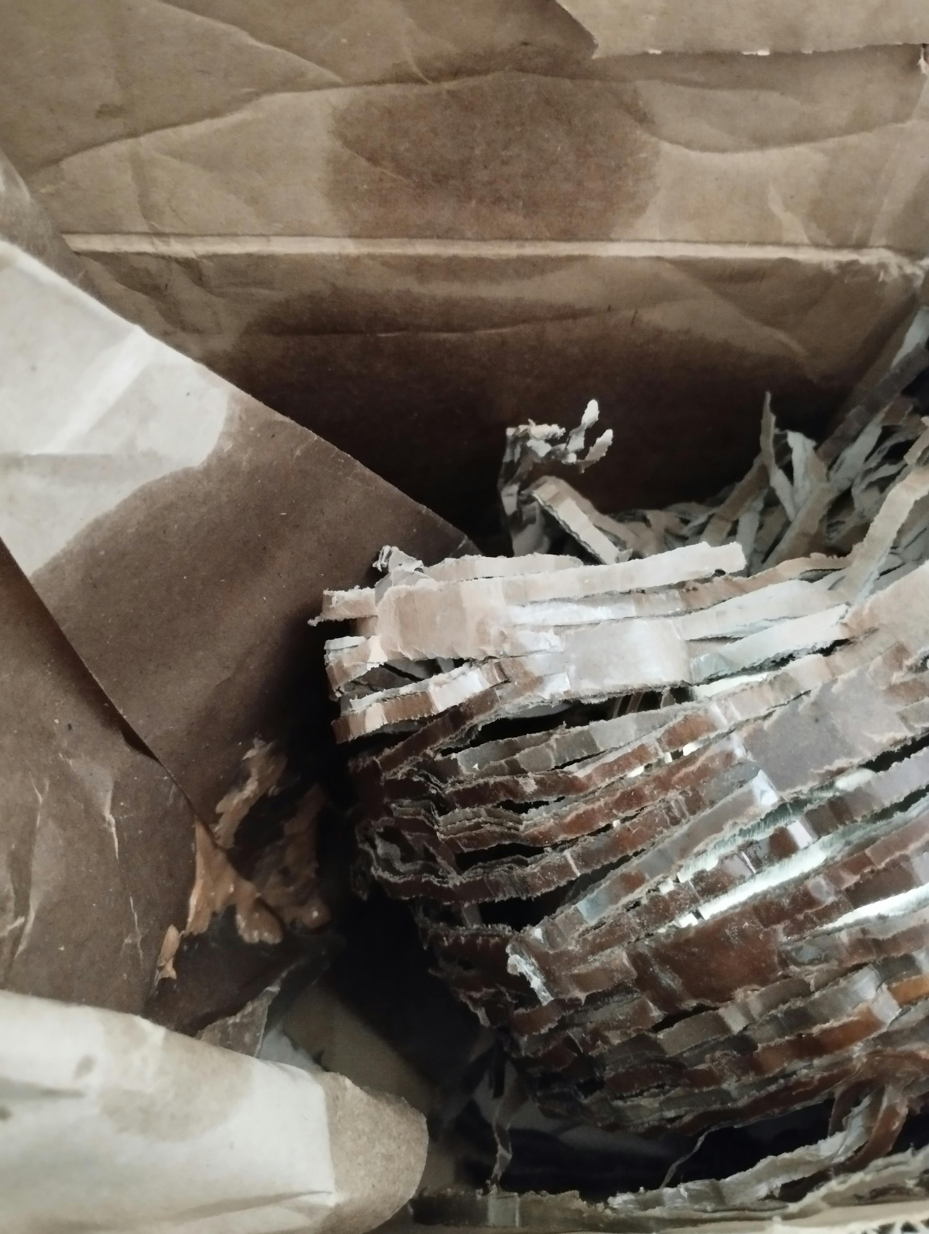 un gros plan d' un sac en papier brun rempli de papier déchiqueté