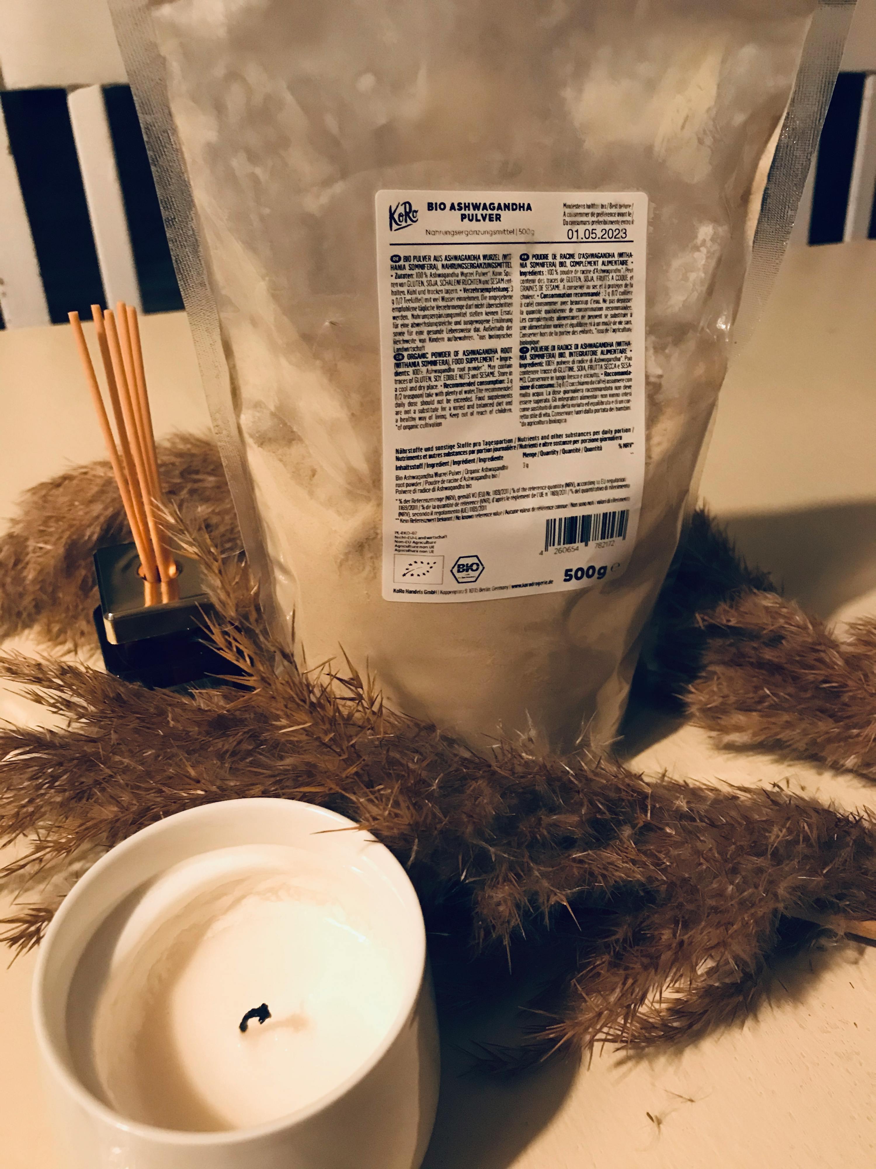 un sacchetto di polvere di ashwagandha è seduto accanto a una candela