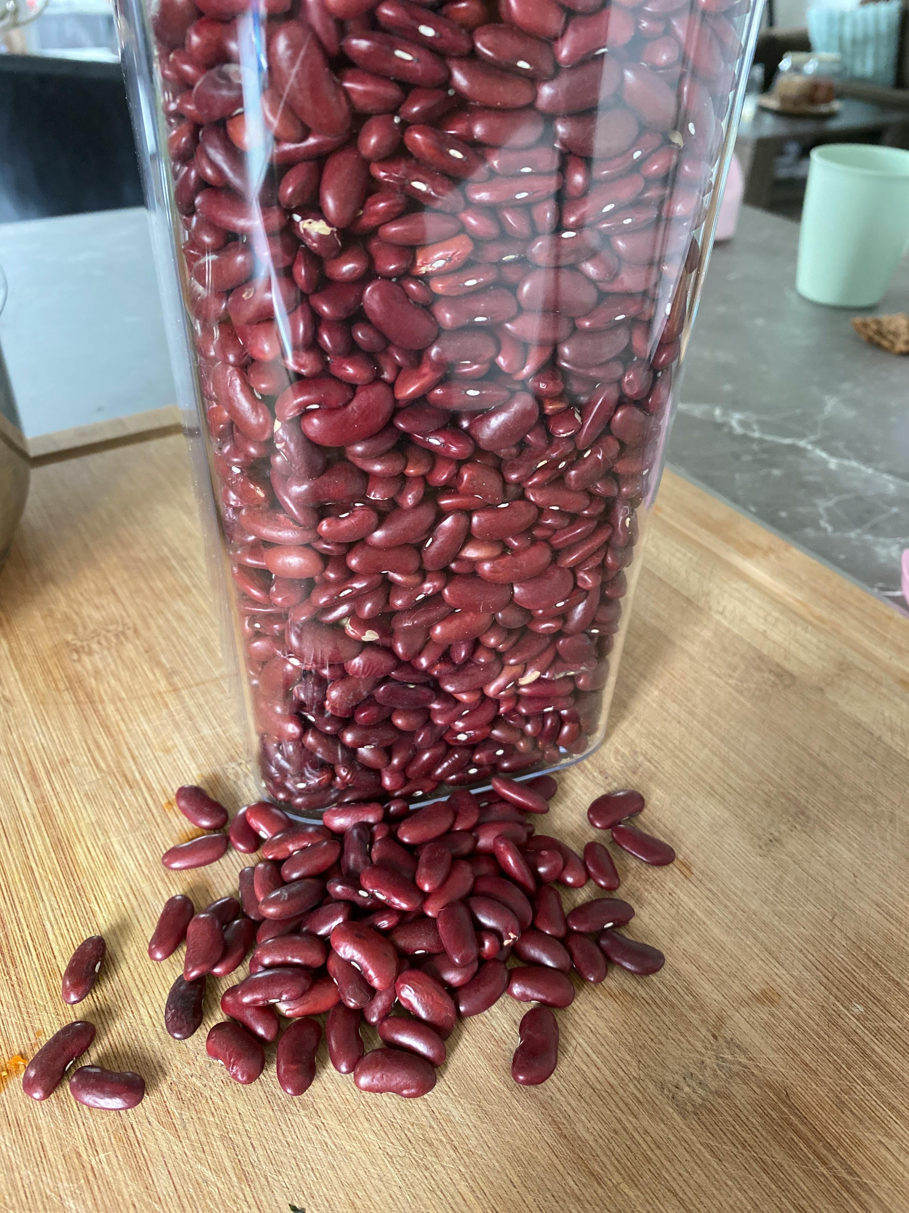 a glass jar filled with red beans on a cutting board