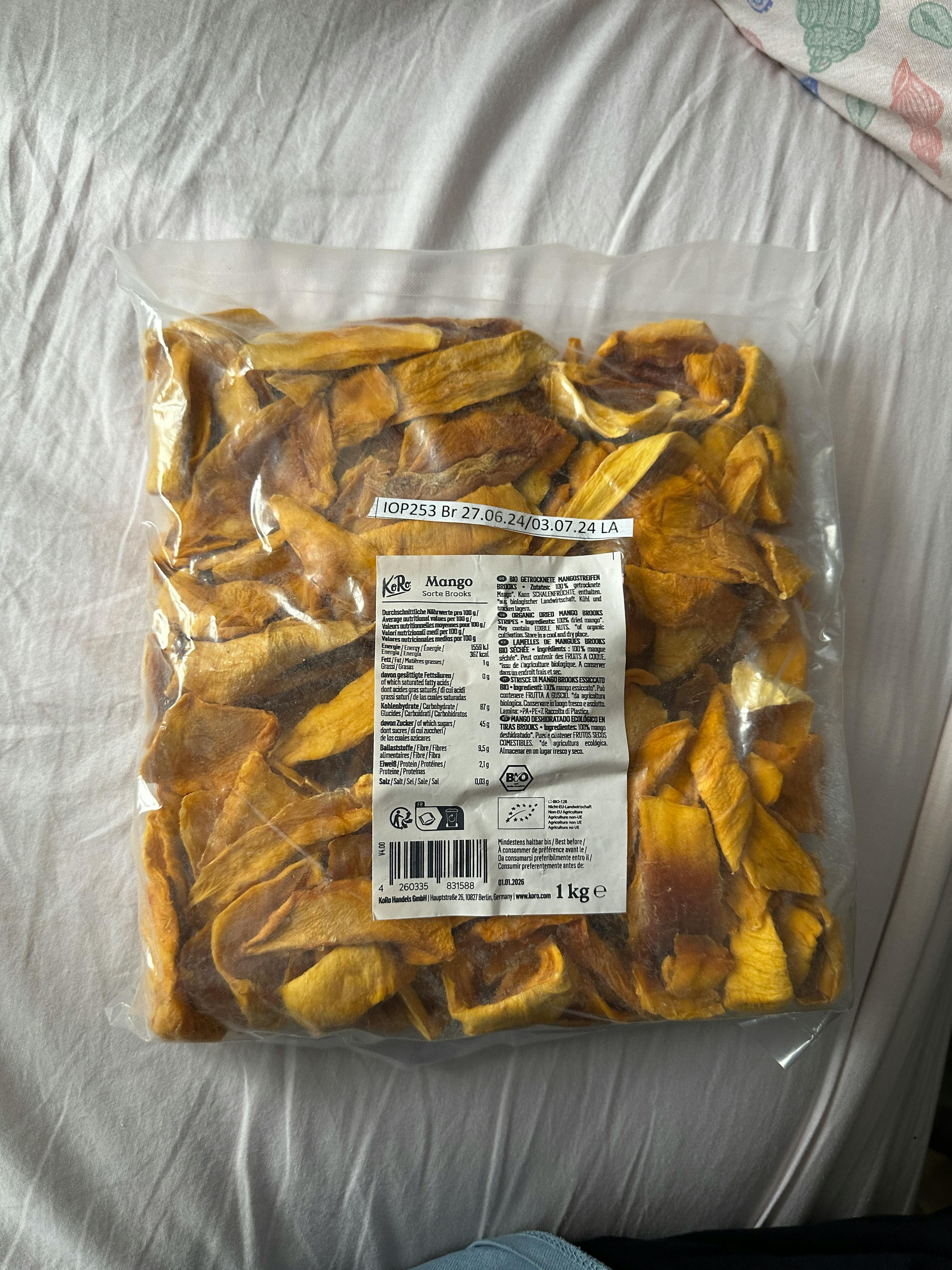 ein Plastikbeutel mit getrockneten mangos liegt auf einem Bett