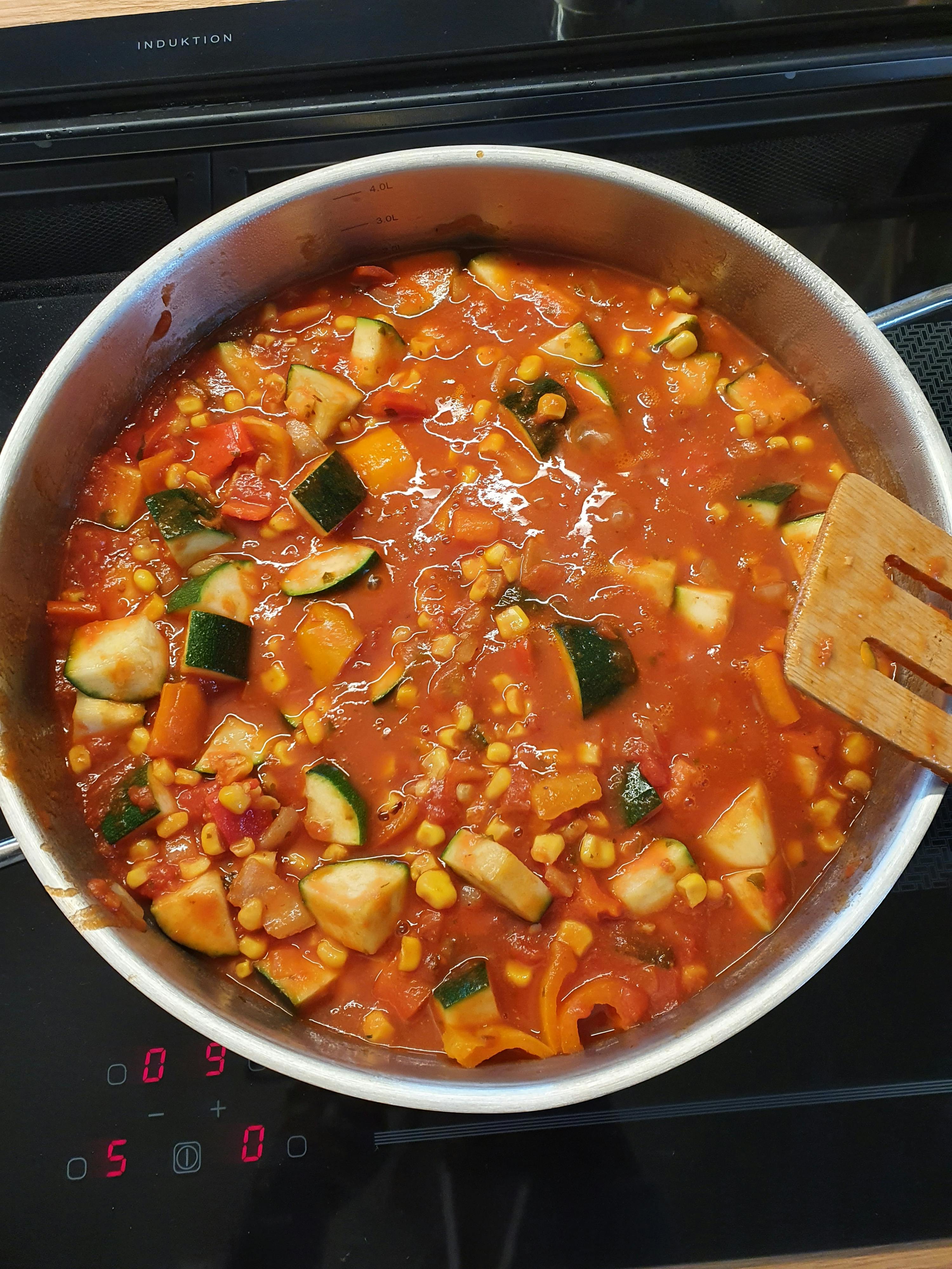 ein Topf mit Gemüse und Tomatensauce steht auf einem Herd