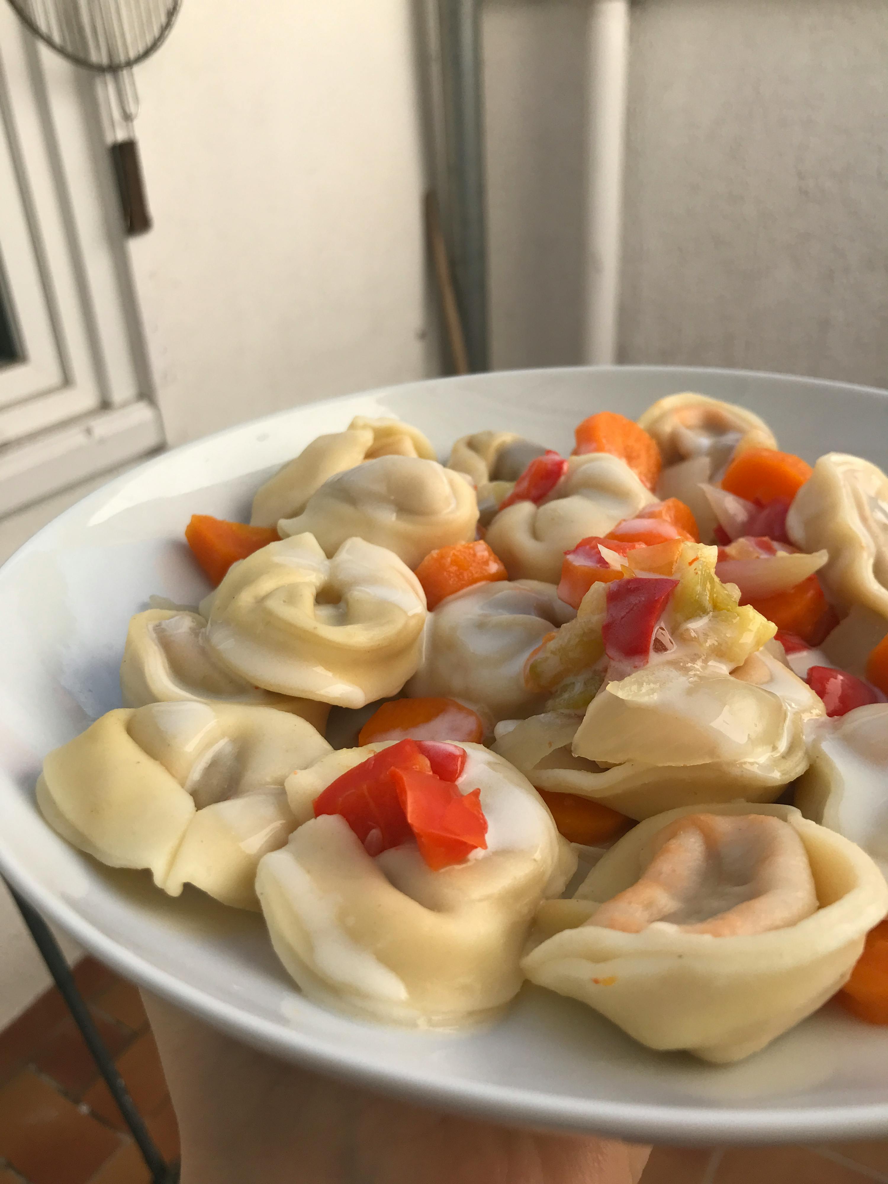 un primo piano di un piatto di tortellini e verdure