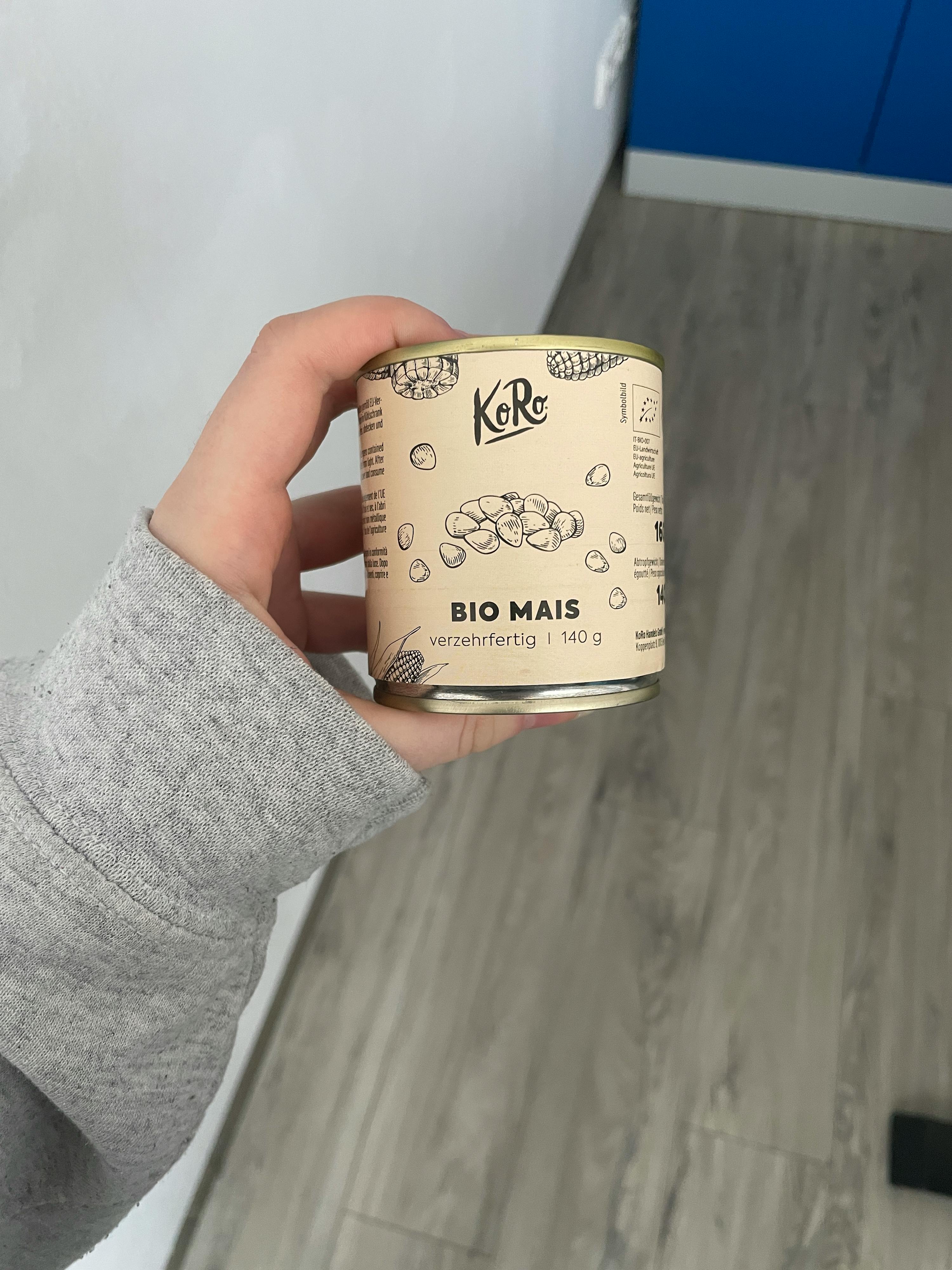 eine Person hält eine Dose bio Mais in ihrer Hand