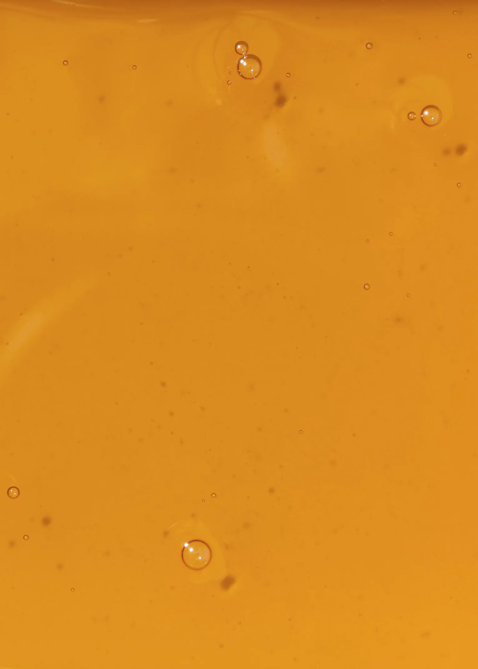 un primer plano de un líquido naranja con burbujas en él