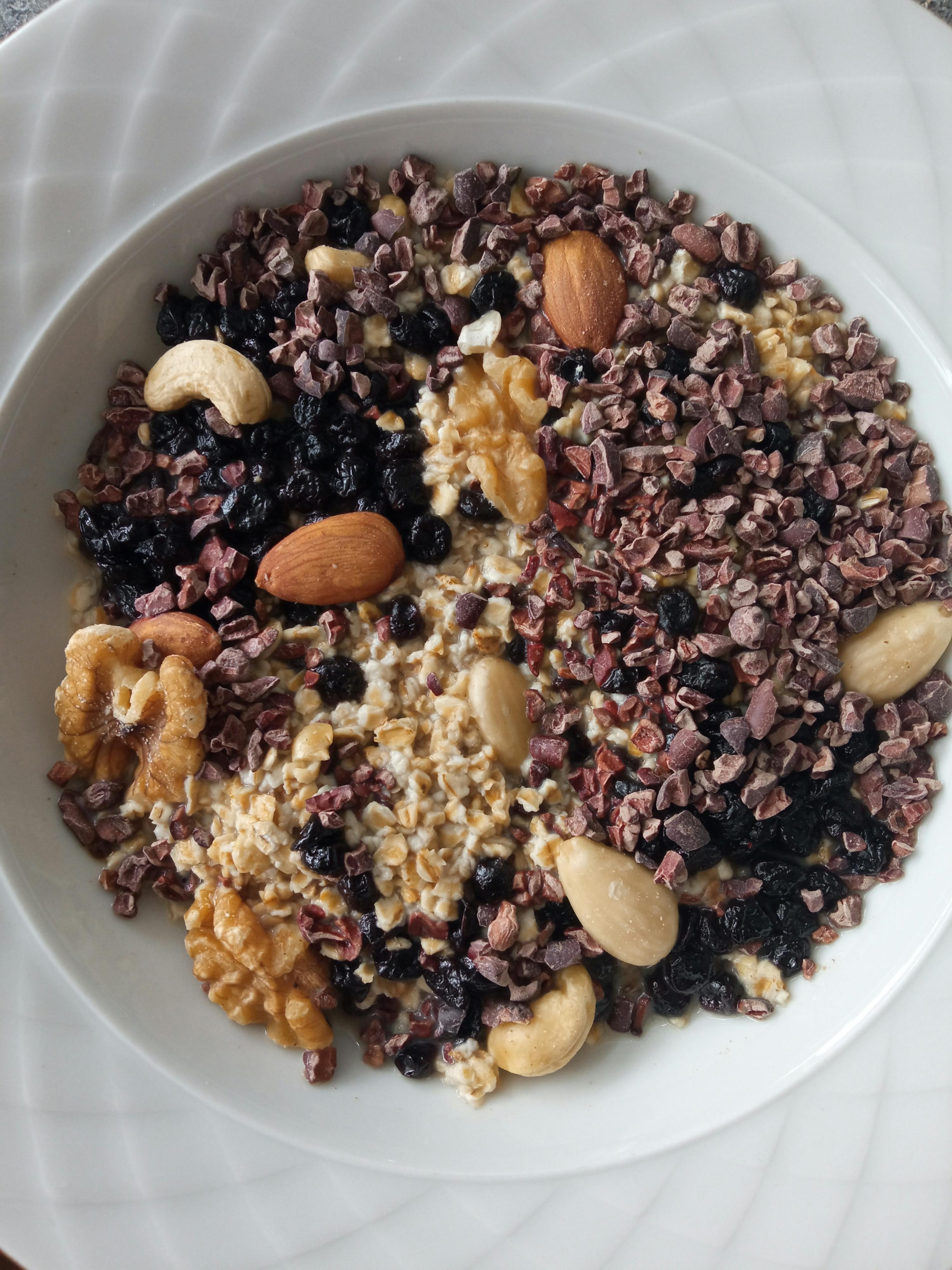 un bol blanc rempli d' avoine , de noix , de raisins secs et de morceaux de chocolat