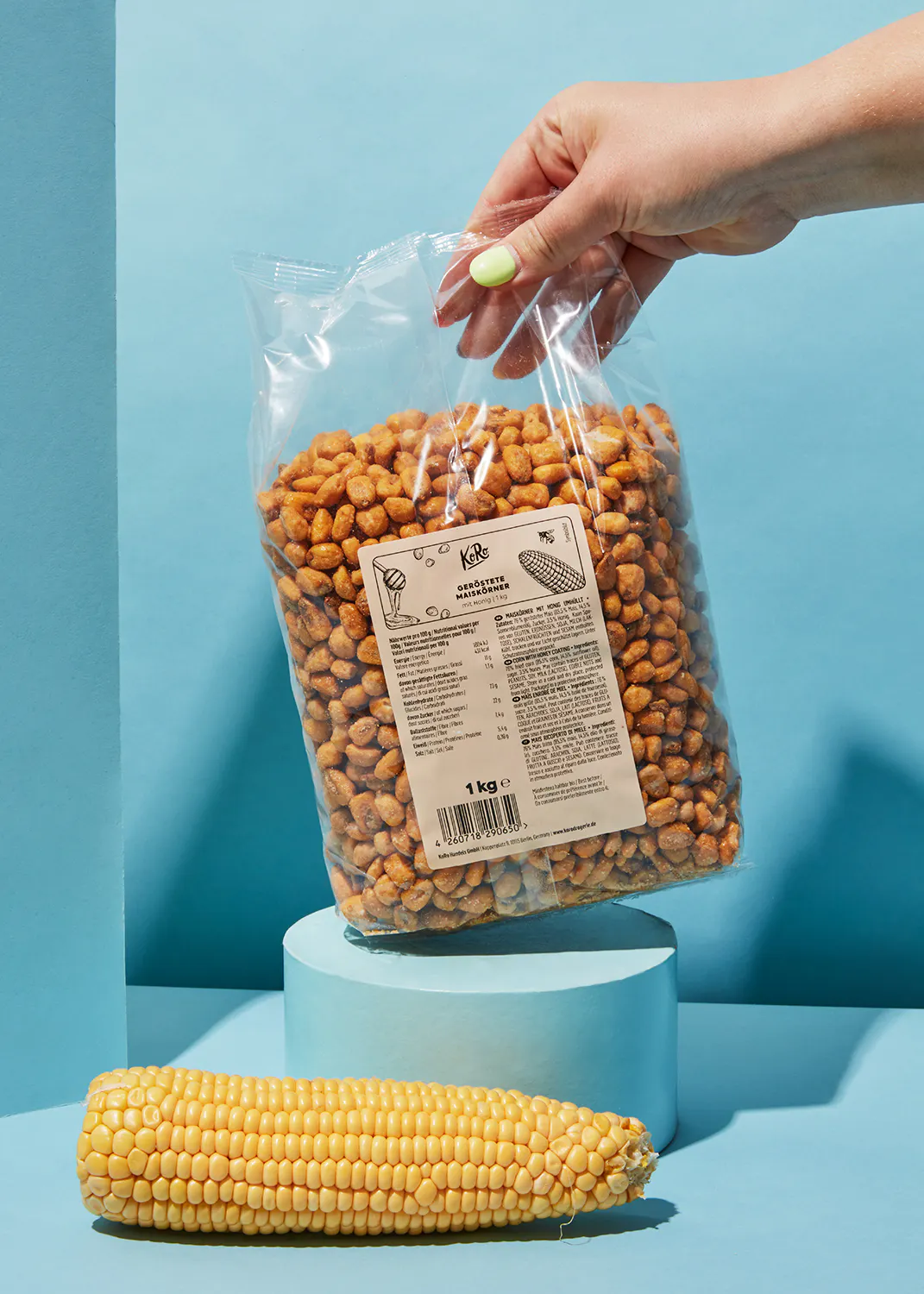 une personne tient un sac de maïs grillé à côté d' une épi de maïs