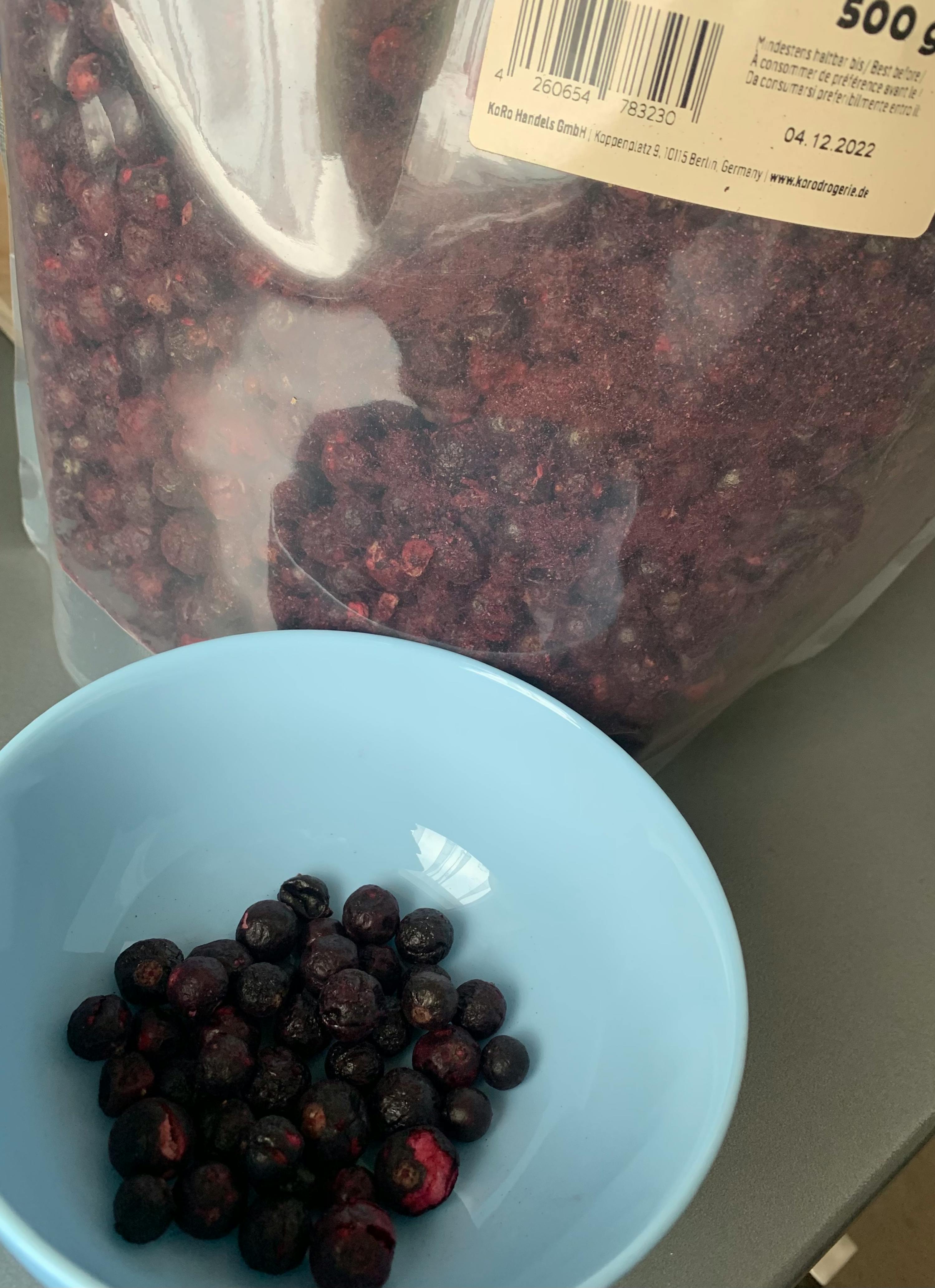 a bowl of blueberries sits next to a bag of blueberries