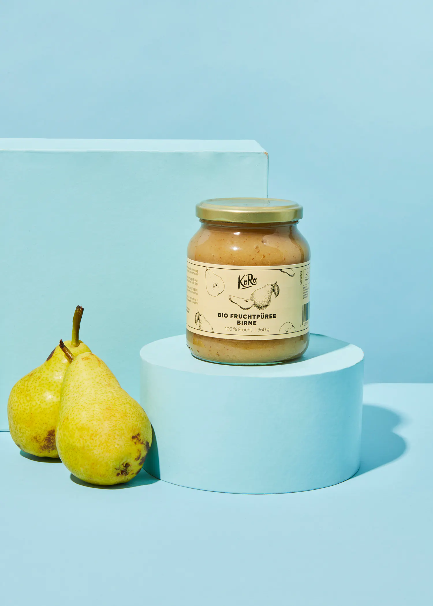 a jar of fruchtpuree sits on a podium next to two pears