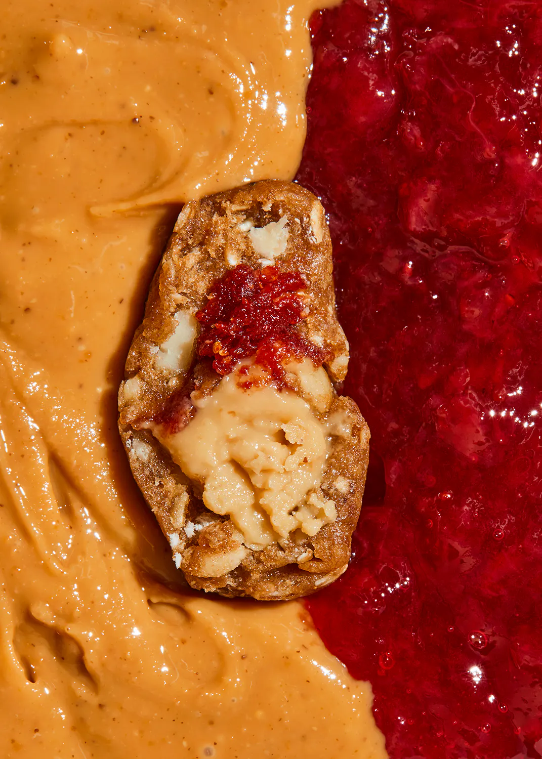 une tranche de pain est couverte de beurre d' arachide et de gelée de framboise