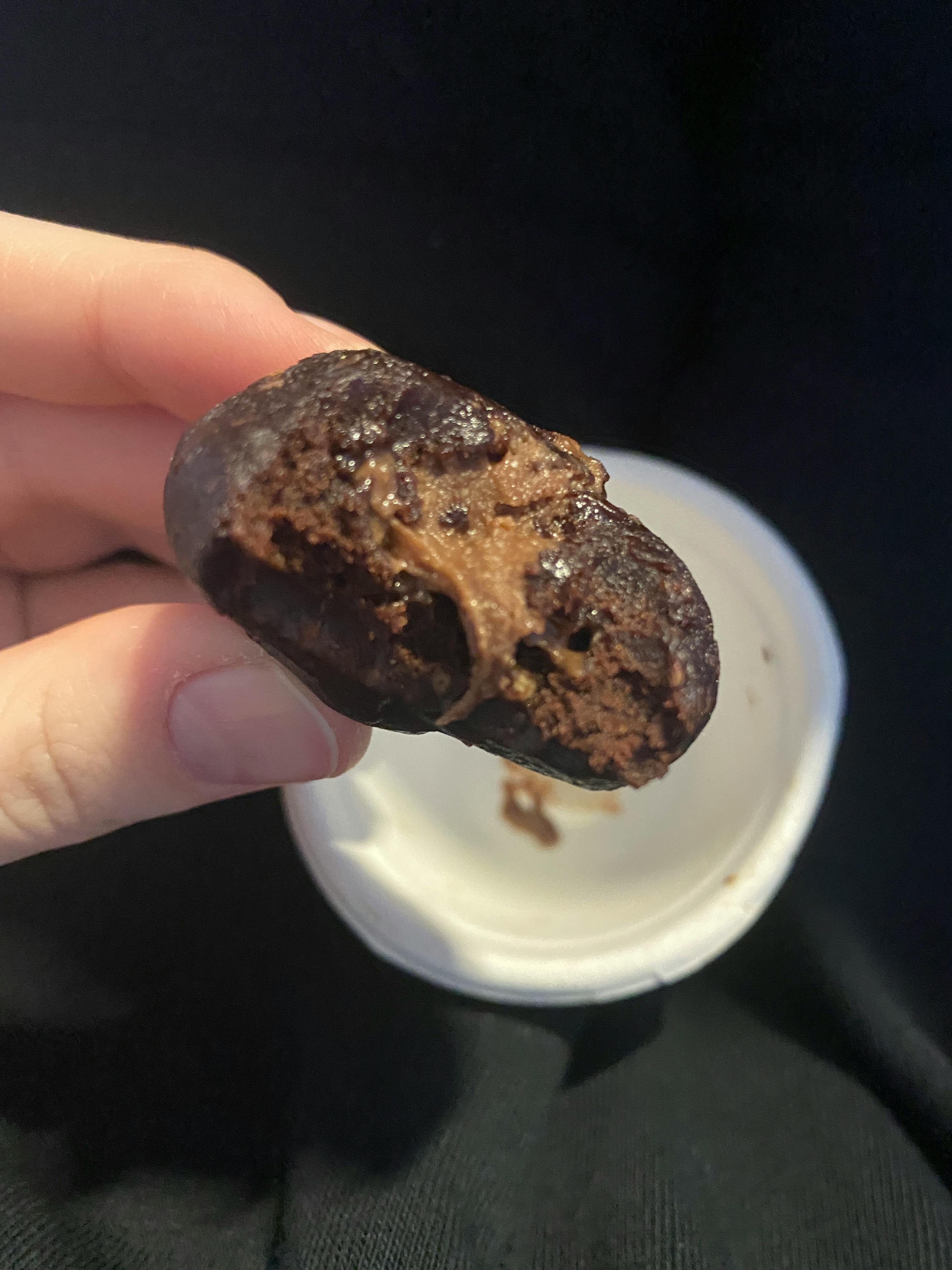 una persona tiene in mano un biscotto al cioccolato con una fetta mancante