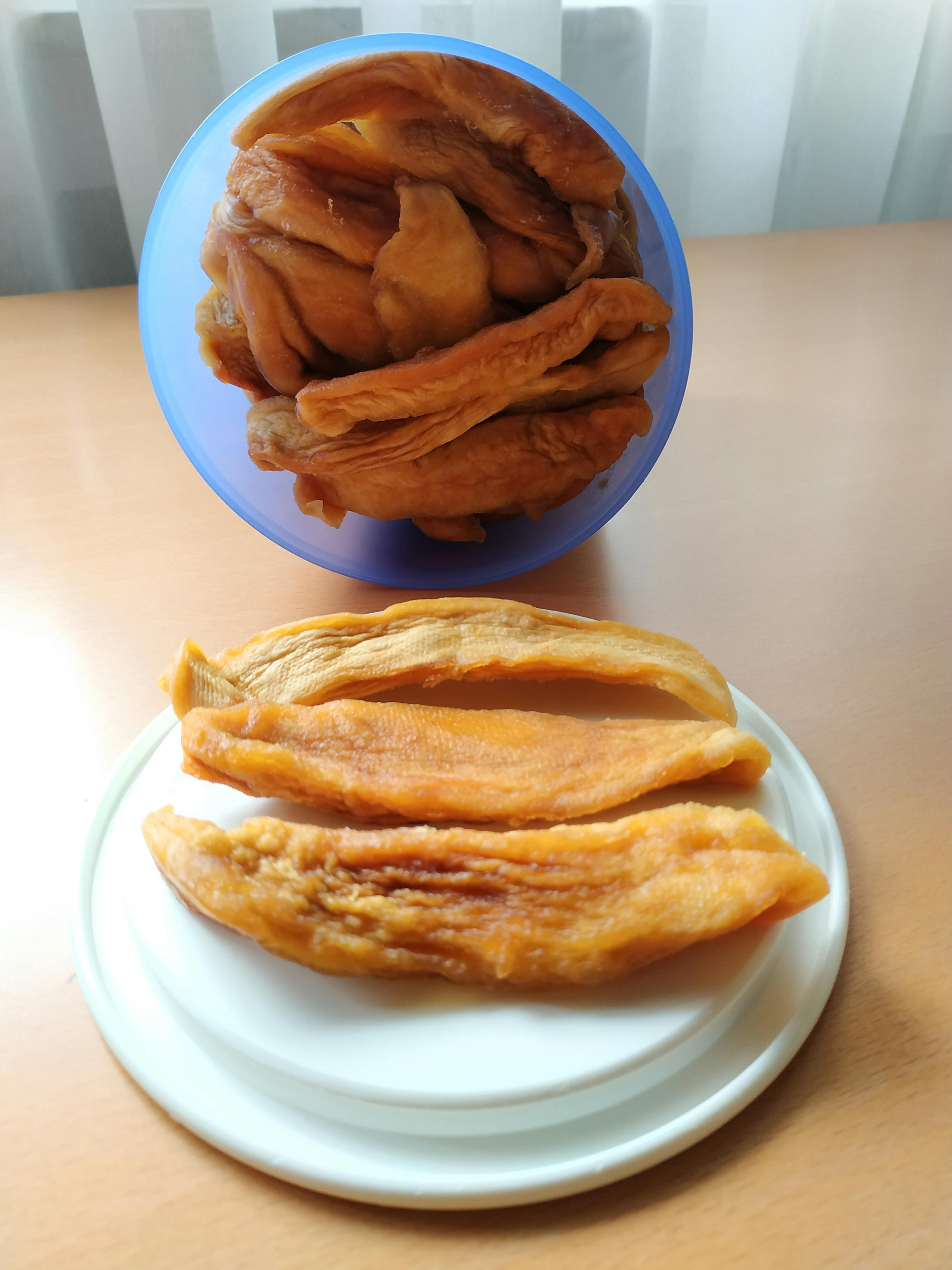 un bol bleu rempli de fruits secs est assis à côté d' une assiette blanche