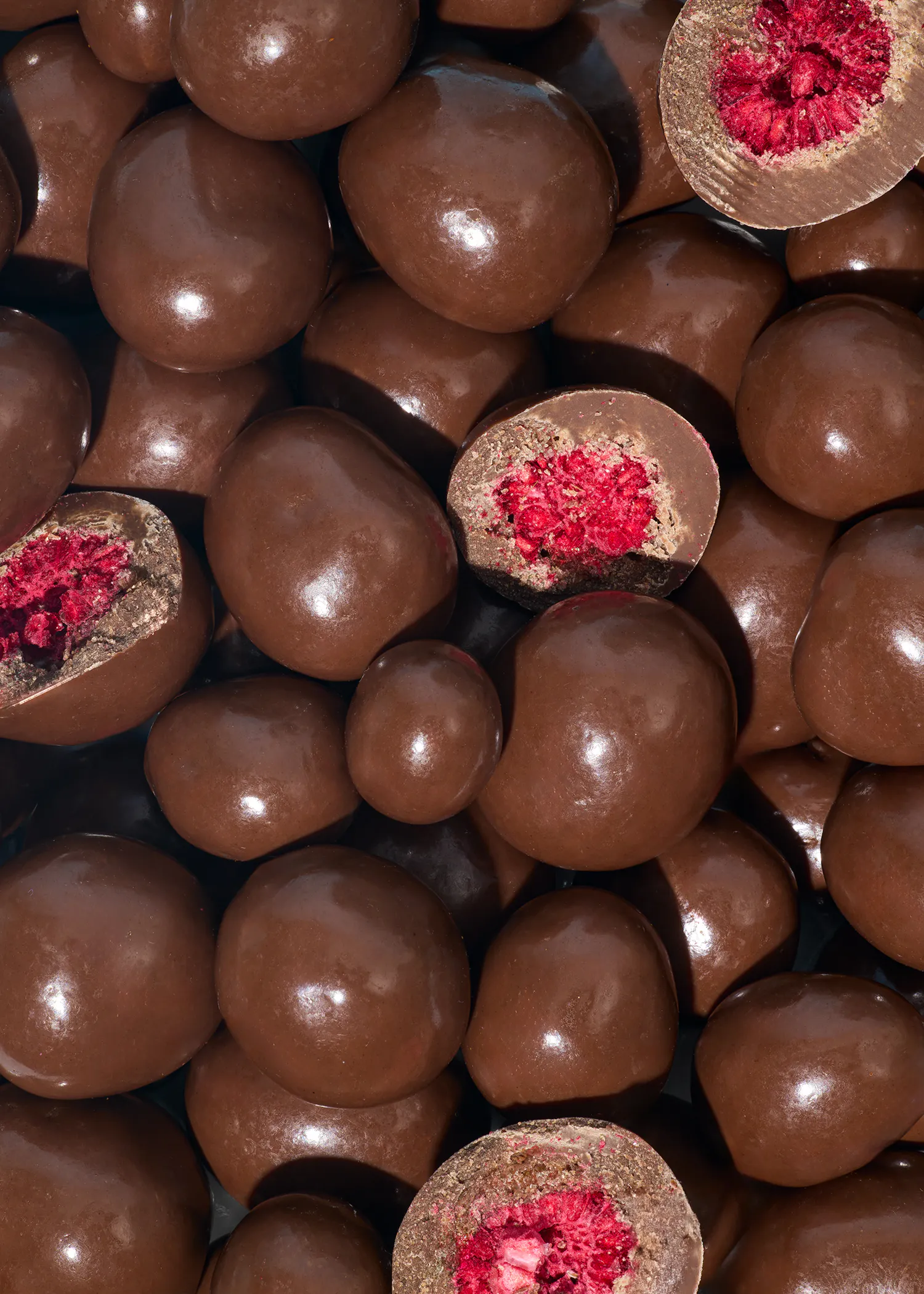 a pile of chocolate covered berries with a raspberry in the middle