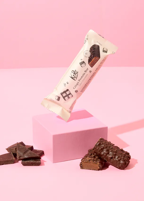 une barre de protéines croustillante posée sur une boîte rose