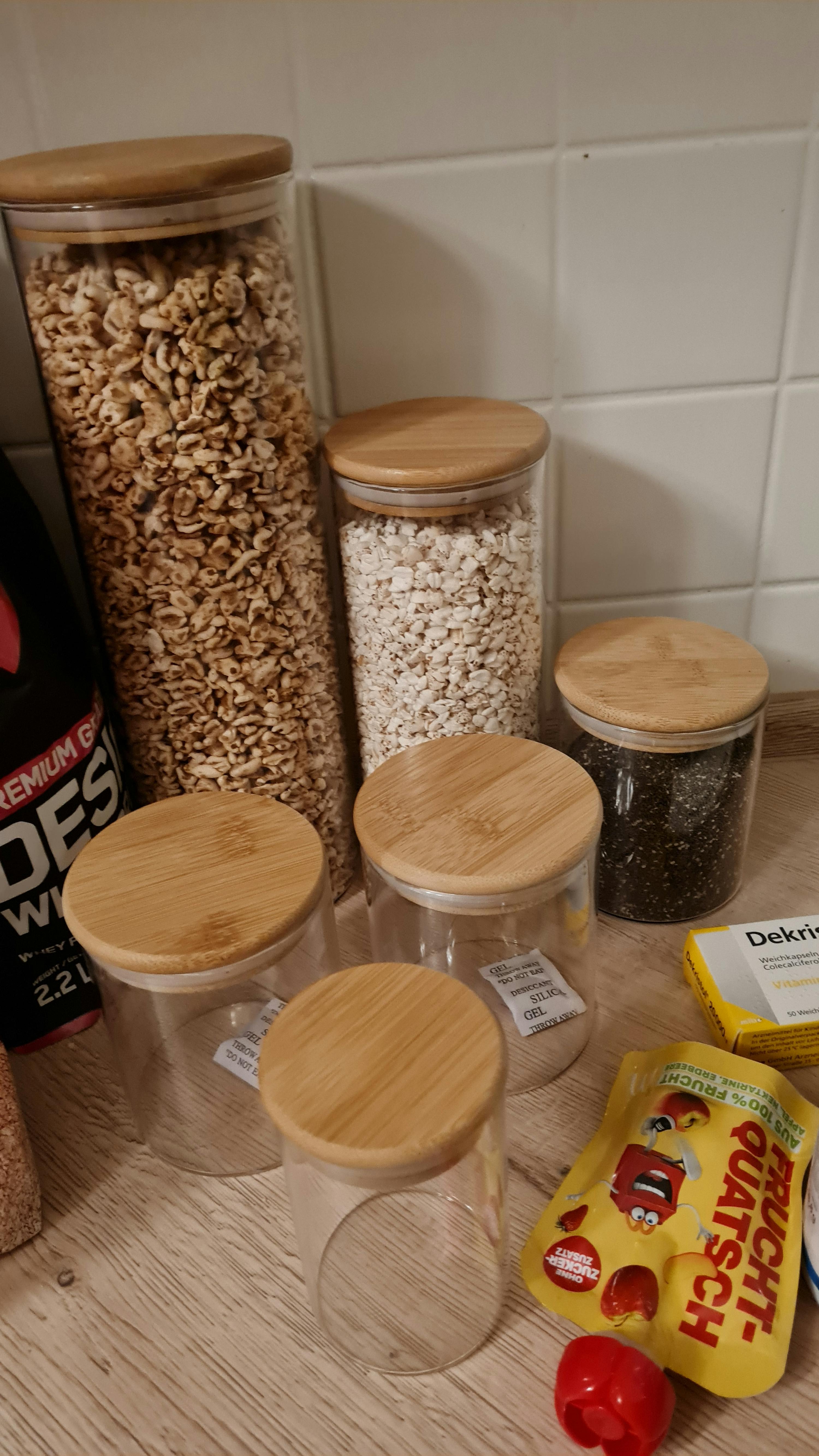 eine Reihe von Gläsern mit Holzdeckeln füllt mit verschiedenen Lebensmitteln