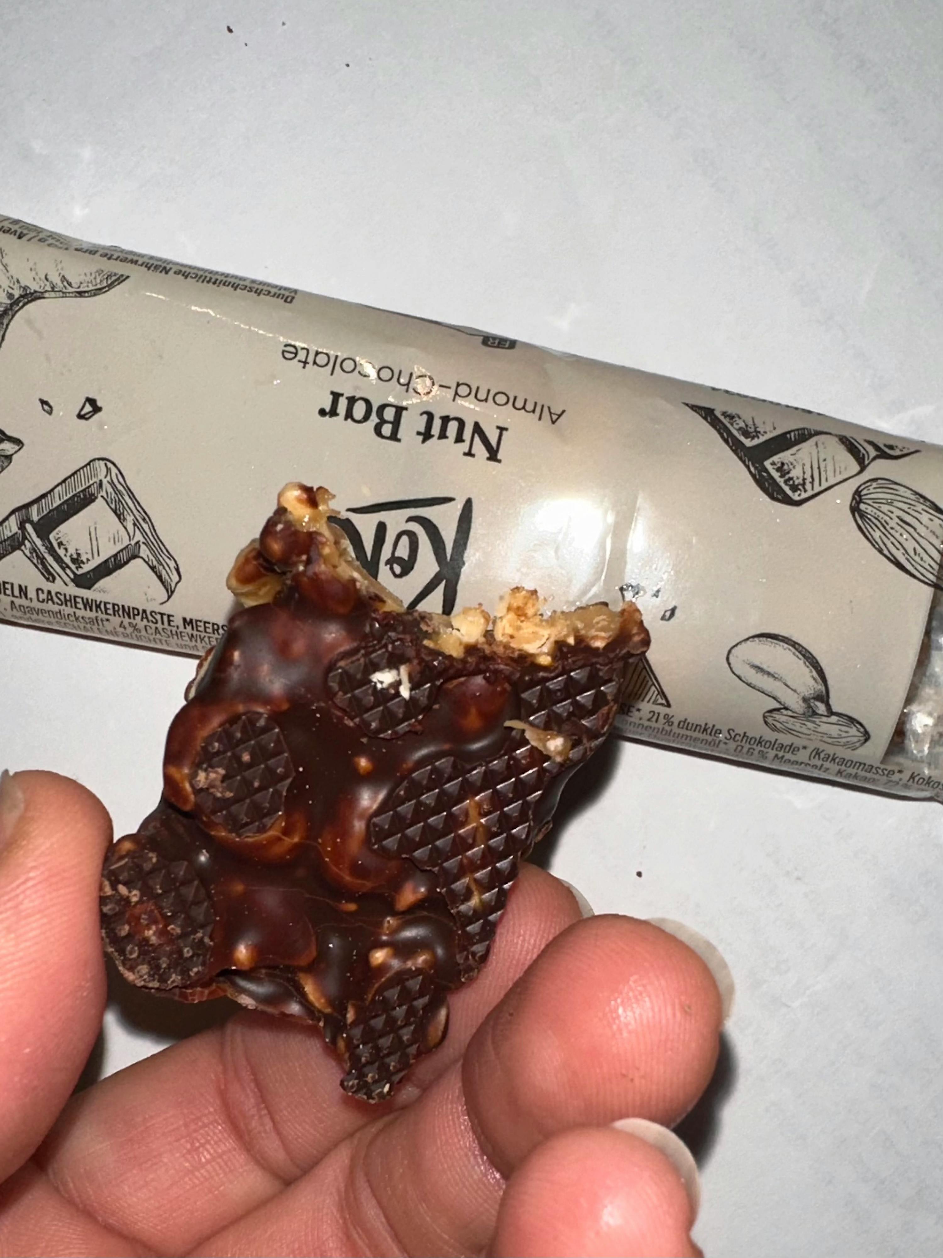 eine Person hält eine Nuss-Schokoladenstange in ihrer Hand