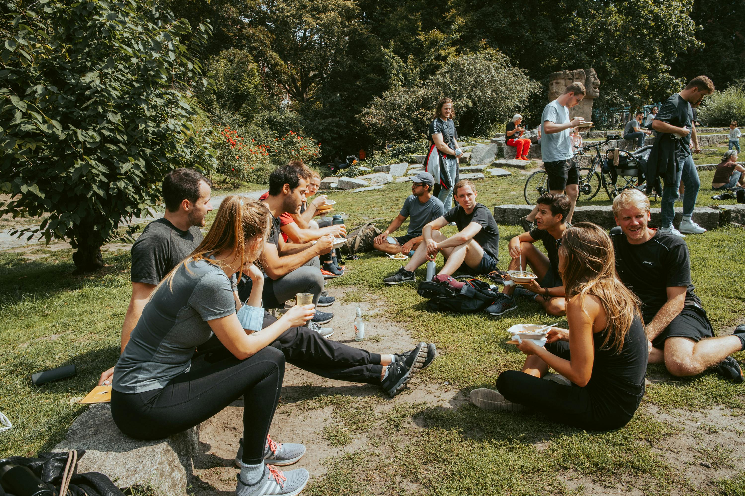 un gruppo di persone si siede in un parco e mangia