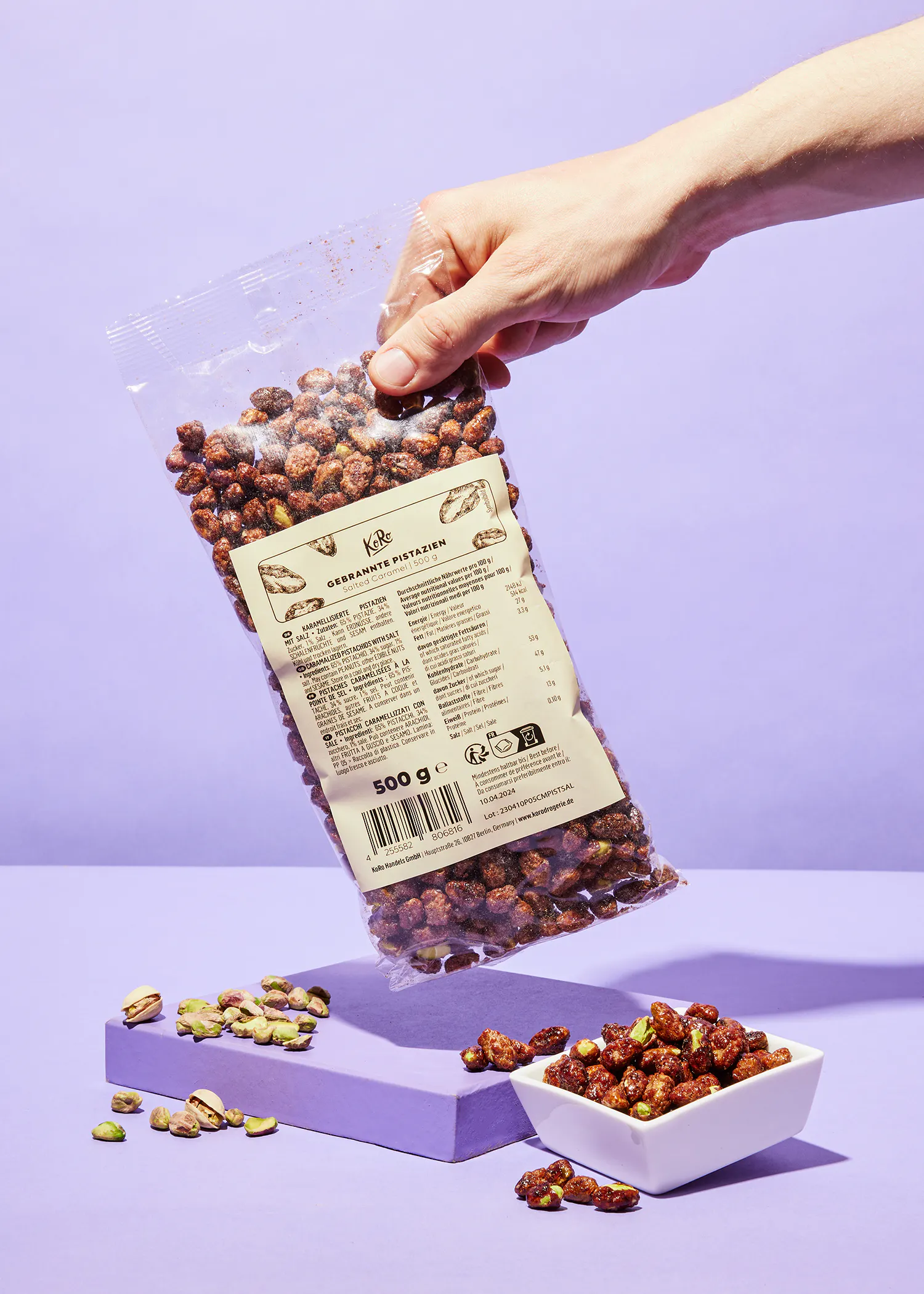 une personne tient un sac de noix de pécan sur une table violette