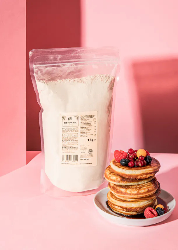 une pile de crêpes sur une assiette à côté d' un sac de farine