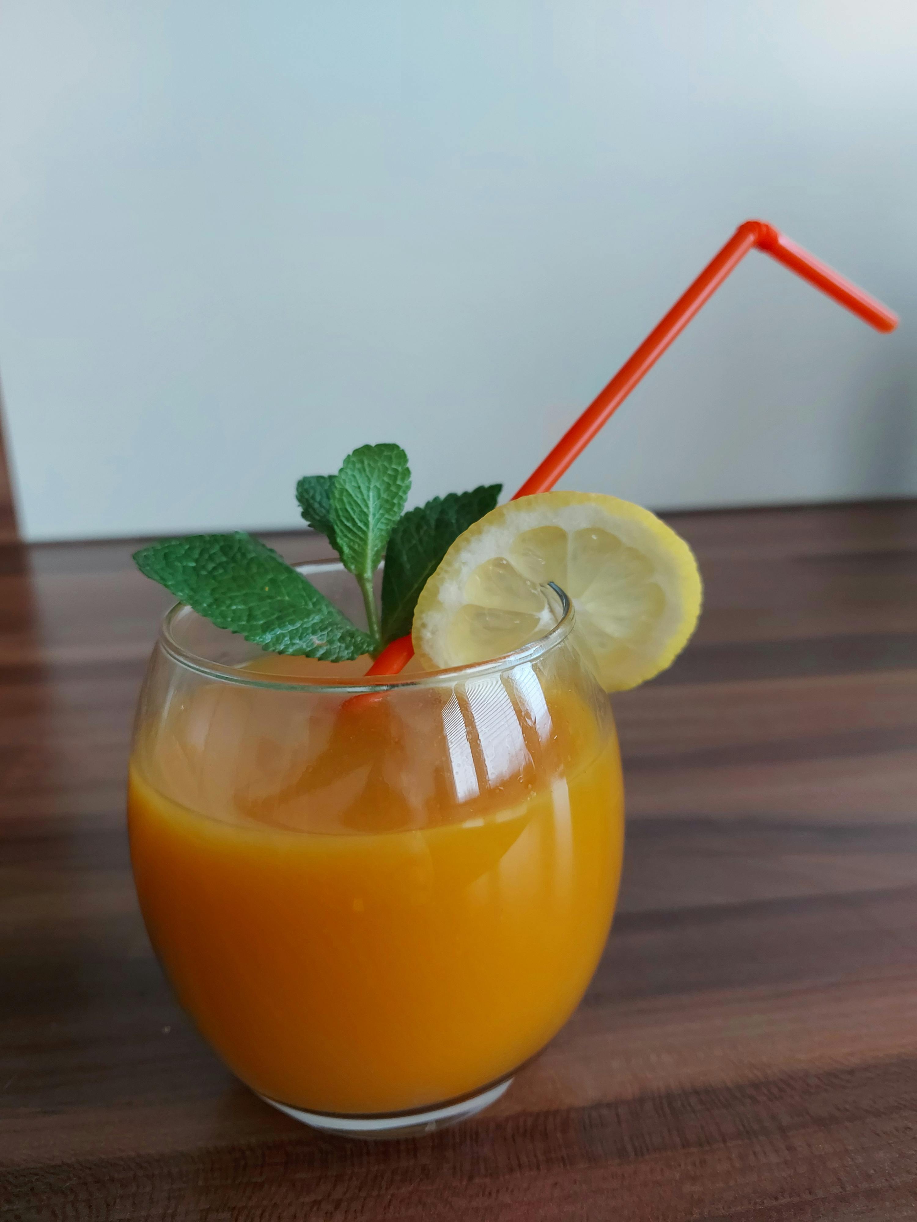 un bicchiere di succo d' arancia con cannuccia e fetta di limone