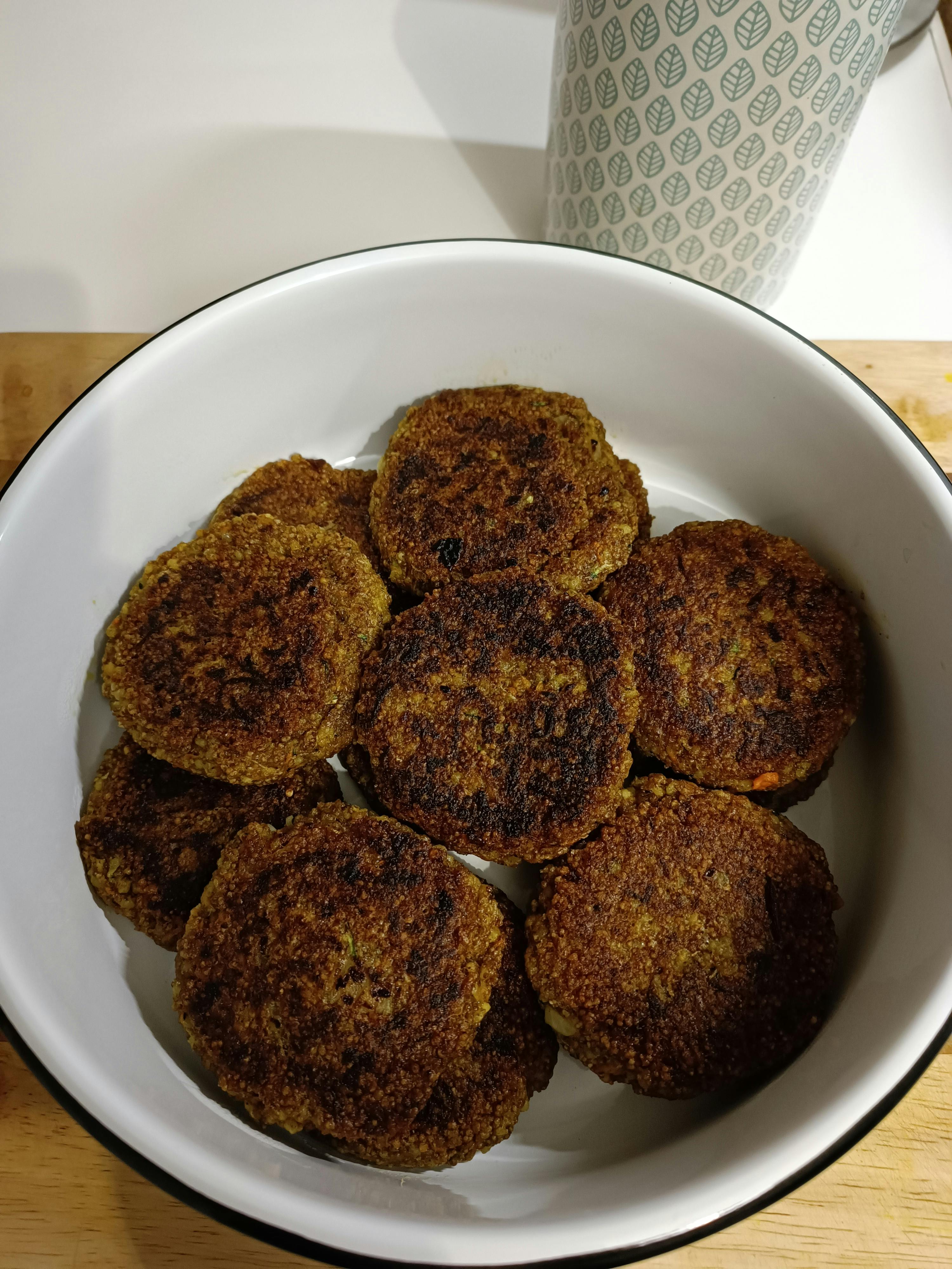 eine weiße Schüssel mit braunen Burgern auf einem Holztisch
