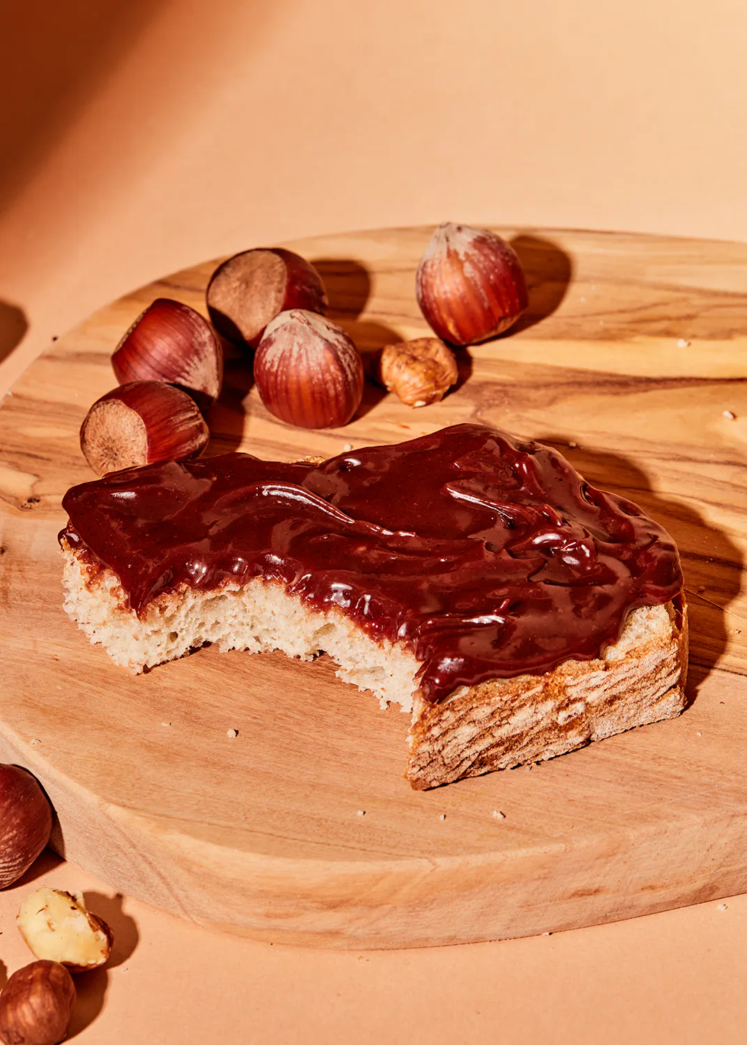 une tranche de pain sur une planche à découper en bois avec des noisettes en arrière-plan