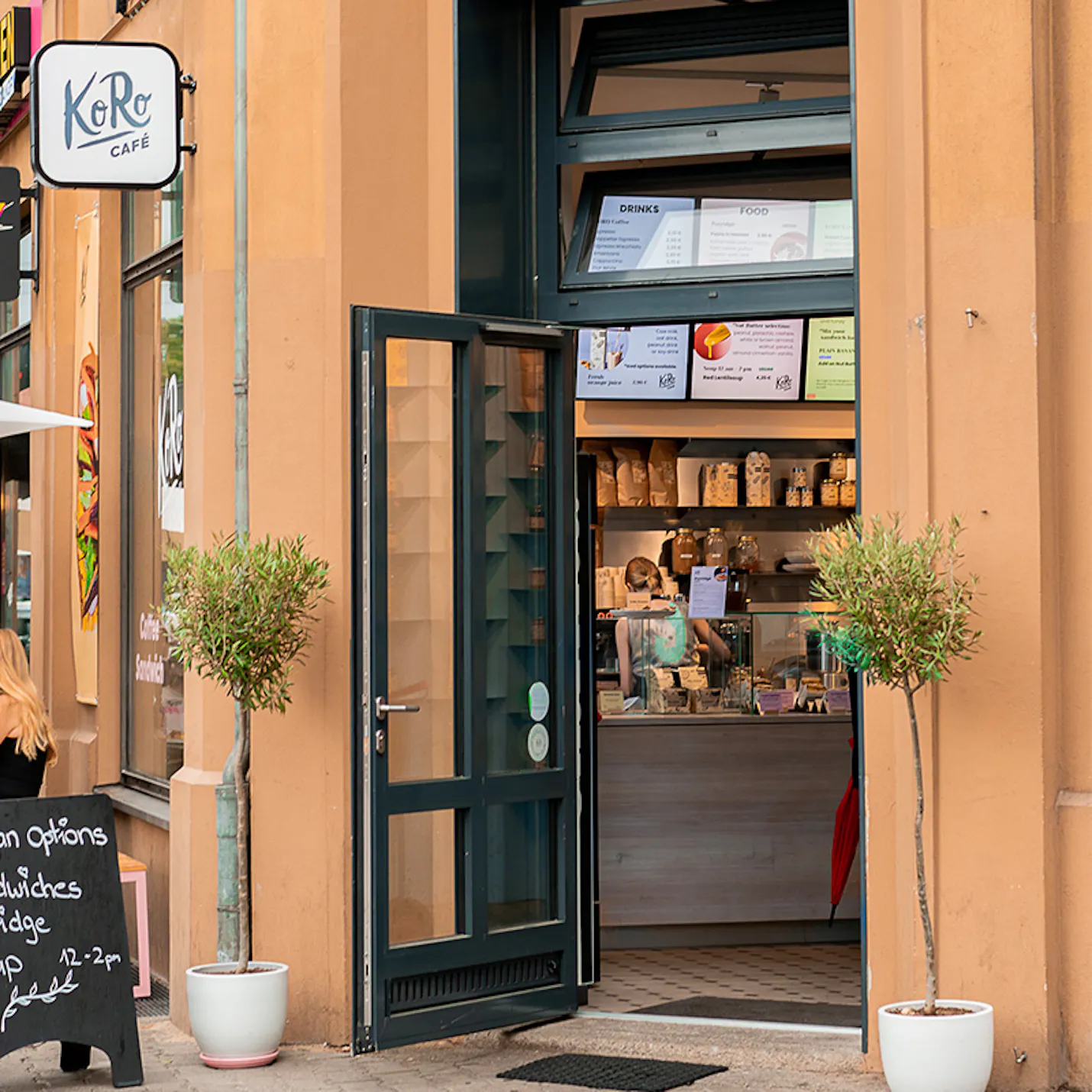 eine Frau steht vor einem Restaurant mit einem Schild mit der Aufschrift " kero cafe "