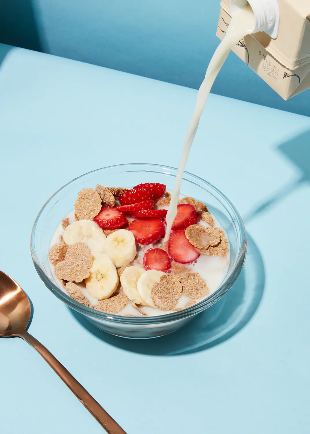 le lait est versé dans un bol de céréales avec des fraises et des bananes