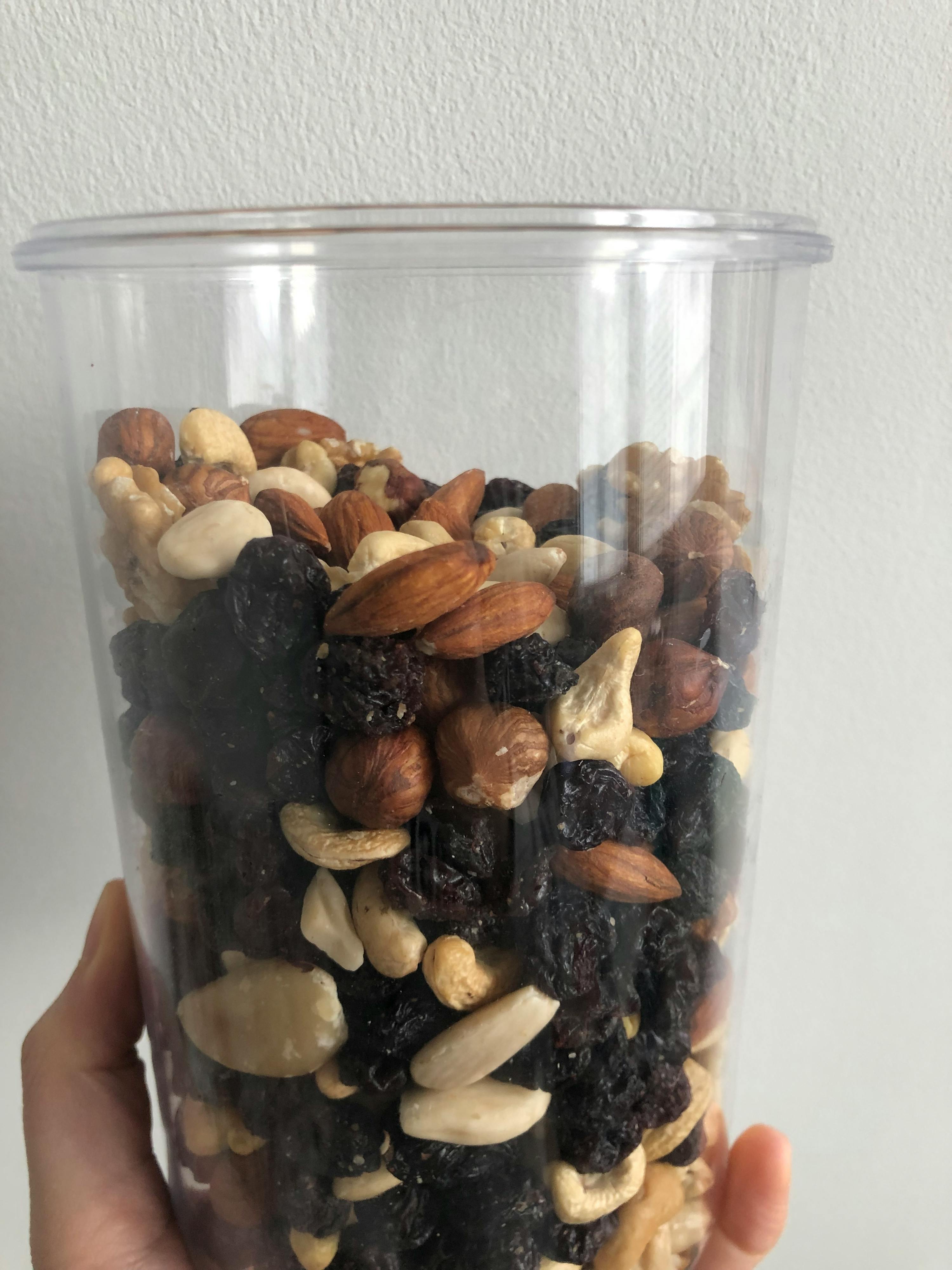 una persona tiene in mano un barattolo di noci e frutta secca