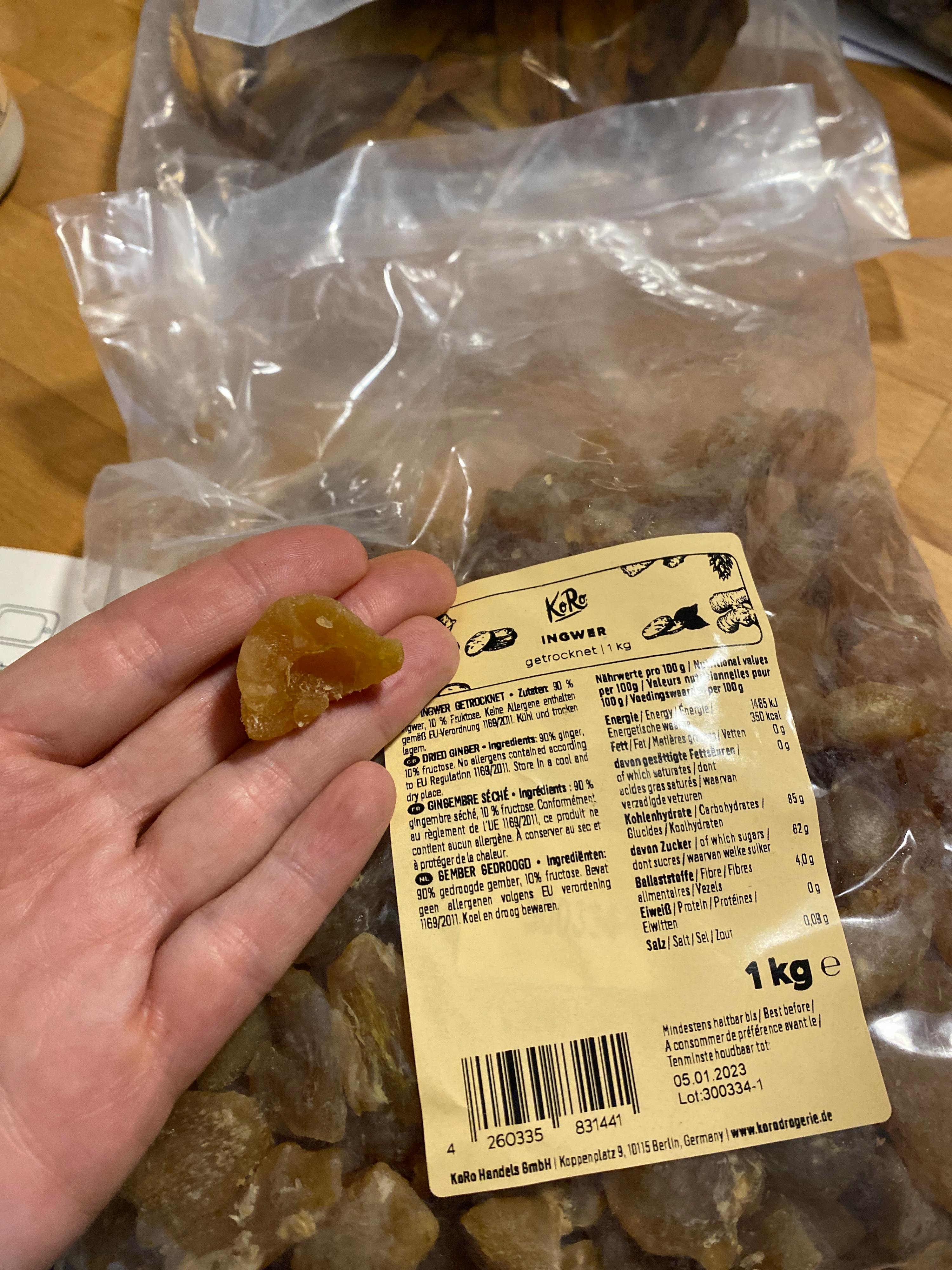 a person is holding a piece of food in front of a bag that says 1 kg