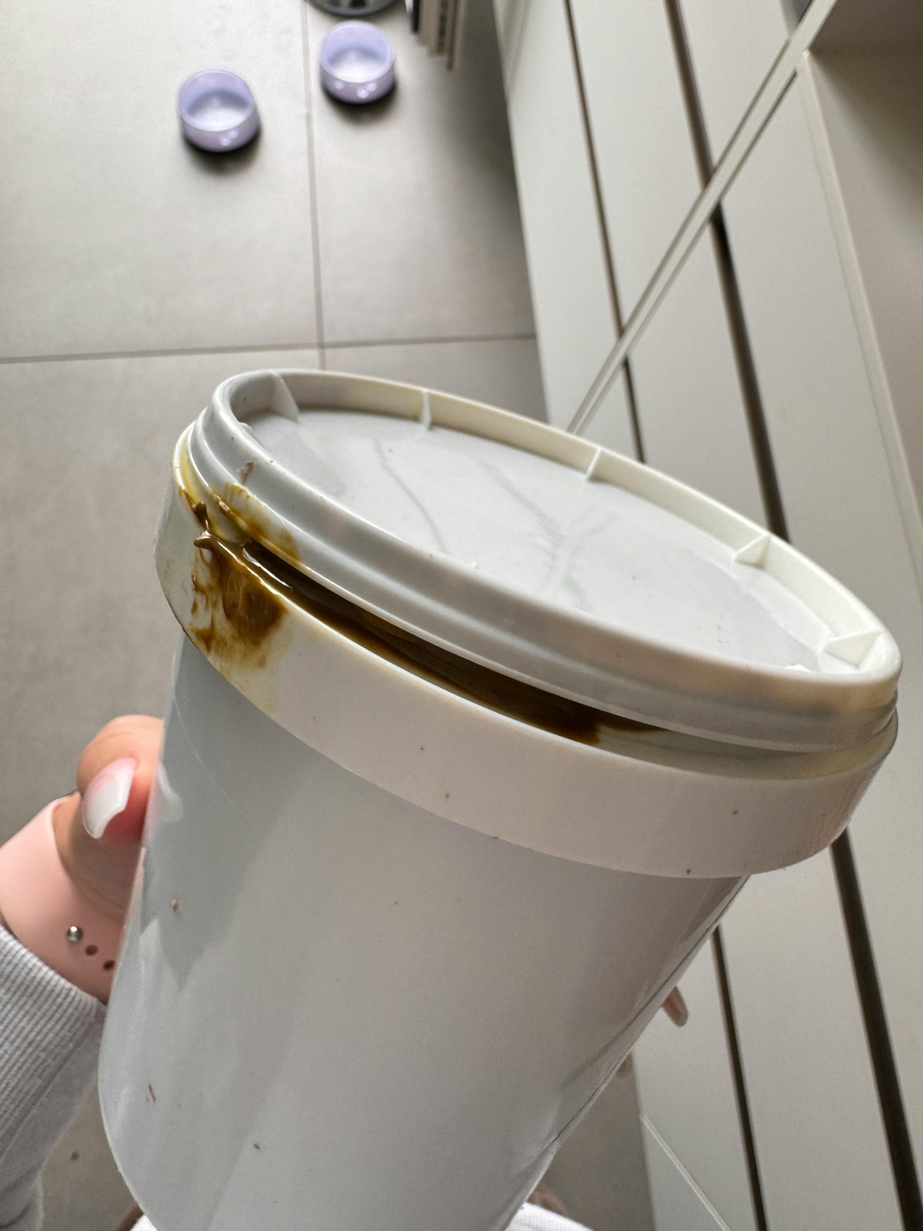 une personne tient un seau blanc avec un couvercle en plastique