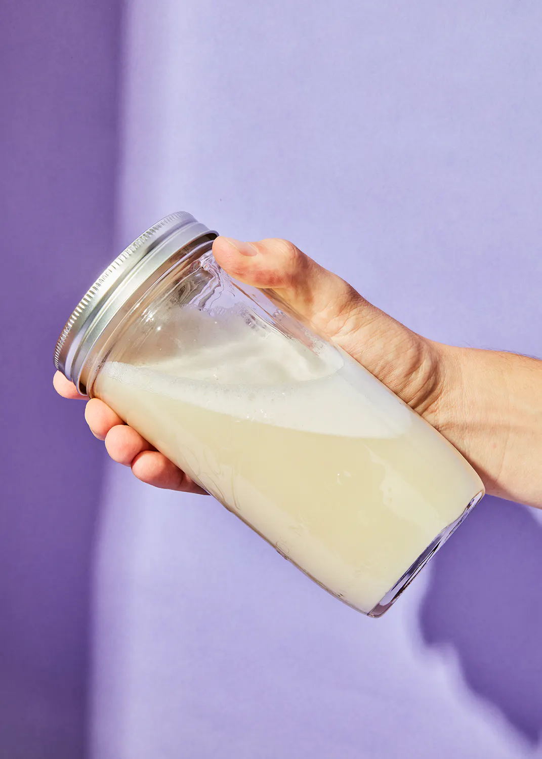 une personne tient un bocal en verre rempli d' un liquide blanc